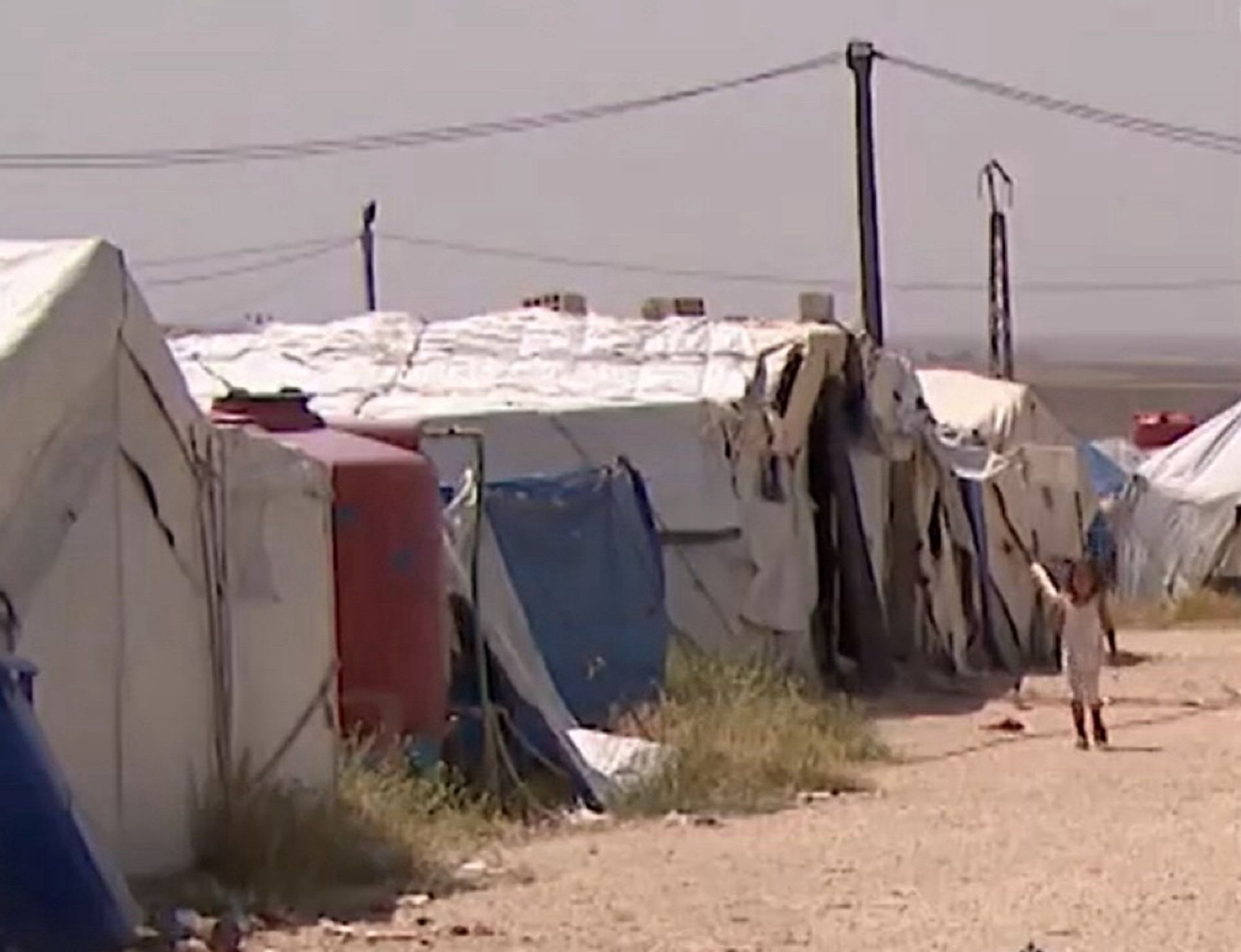 Un enfant au milieu des tentes dans un camp.