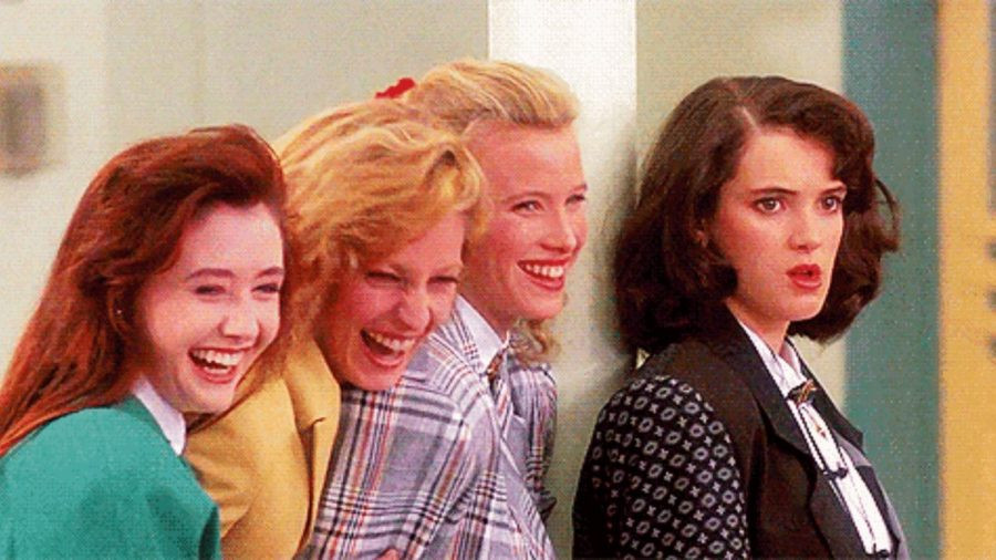 Still from the film Heathers featuring 4 young women. 3 are laughing, one is not.