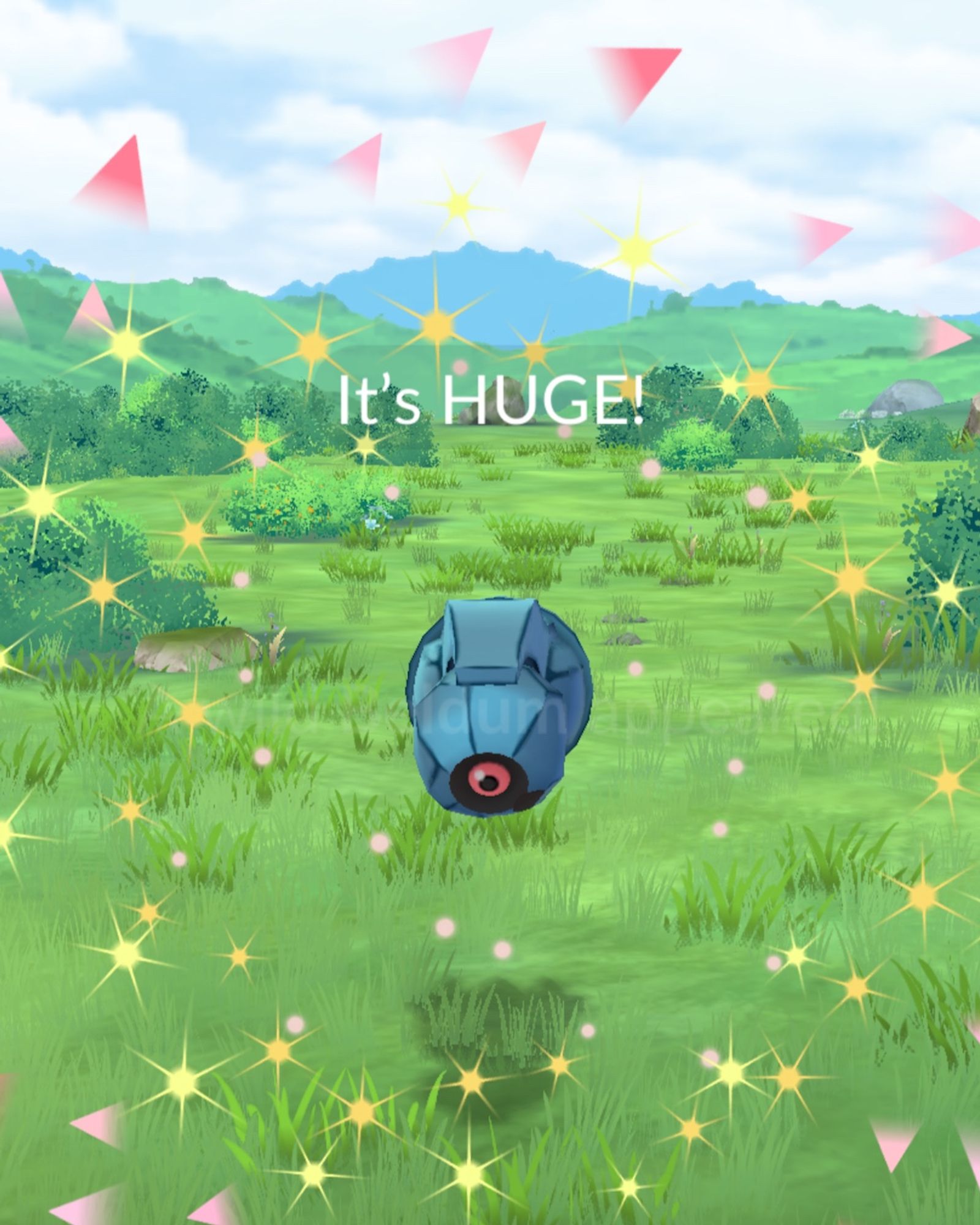 Screenshot of the catch screen in Pokémon GO, showing a Beldum and the visual effect to denote that its size is extra, extra large for this species of Pokémon. Text above Beldum reads, “It's HUGE!”