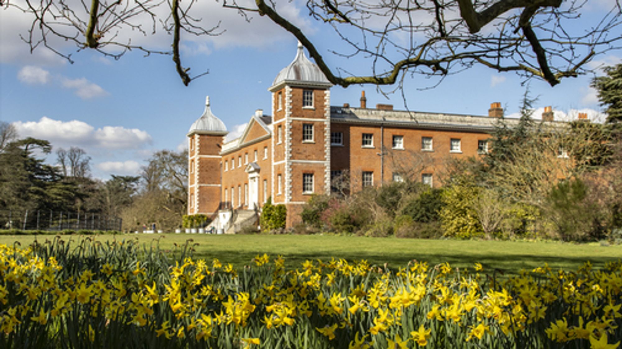 External view of a corner of Osterley House, London and its gardens with daffodils flowering. Osterley is a National Trust property.