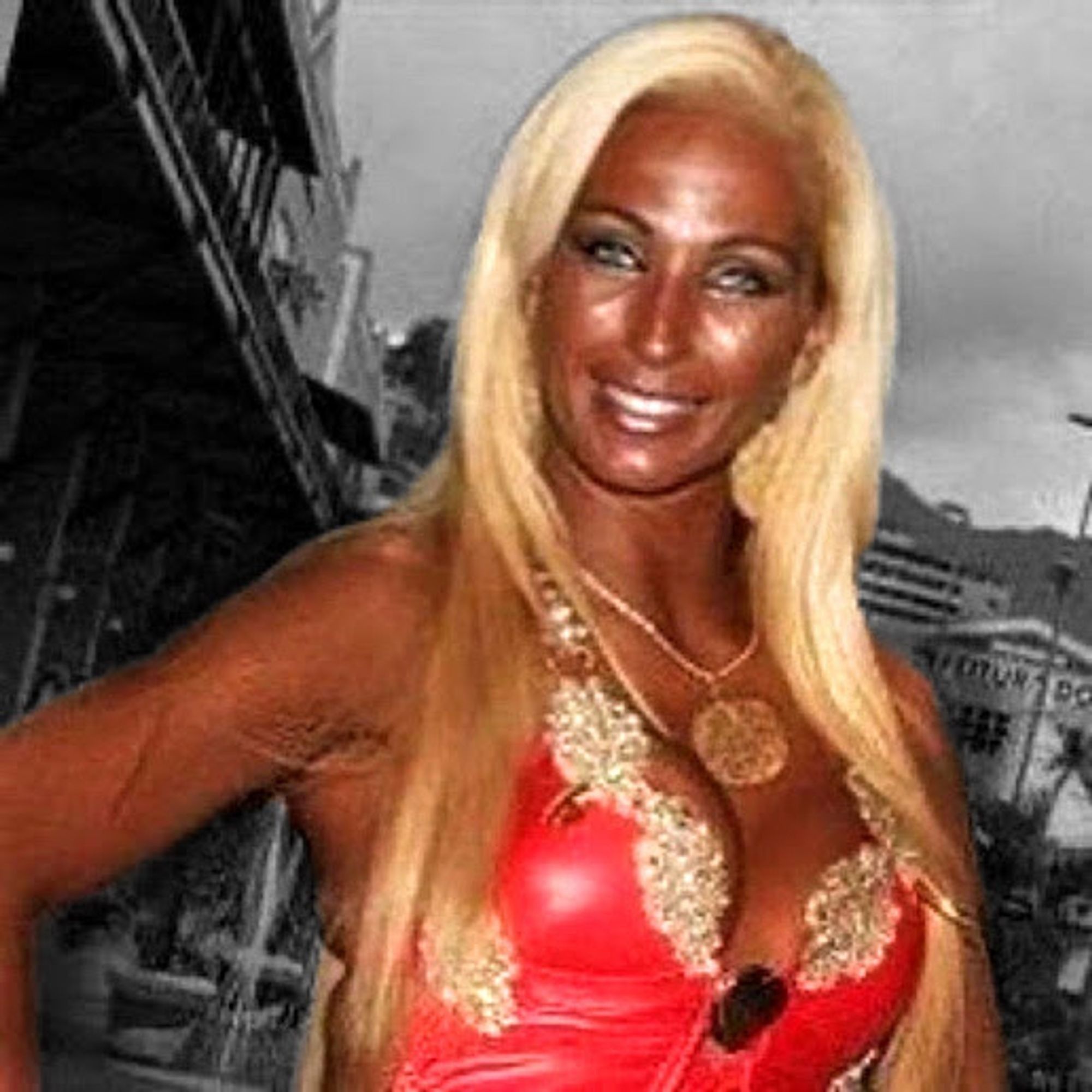 Valesca popozuda com cabelo loiro claro com bronzeado extremamente exagerado posando com mão na cintura sorrindo dura para camera