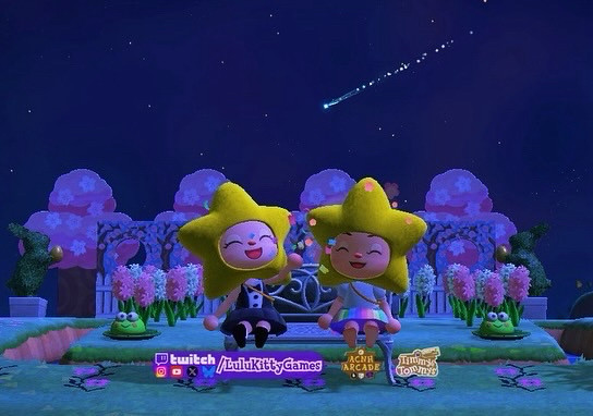 Animal crossing new horizons scene where Yaumy and Lulukitty characters are both wearing the star head item in-game. Yaumy is also wearing the chic tuxedo dress and throwing confetti and smiling. Lulukitty is wearing a custom pastel rainbow dress. Reply for custom code. They are sitting on a garden bench with cherry blossom standees and pink and white hyacinth flowers in the background.