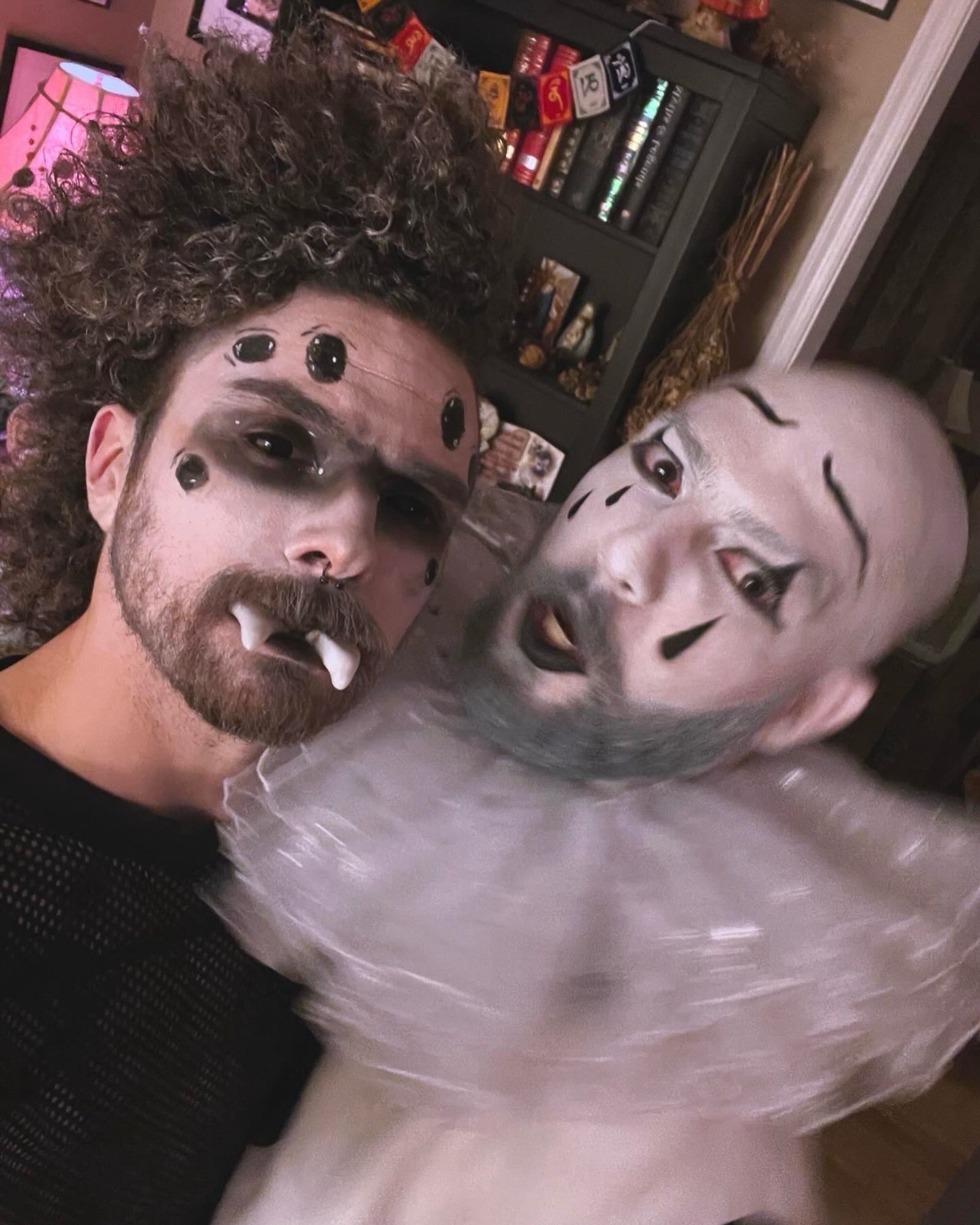 A photo of Connor in face makeup resembling a spider and a bald person completely painted white with a clown face and tears painted on