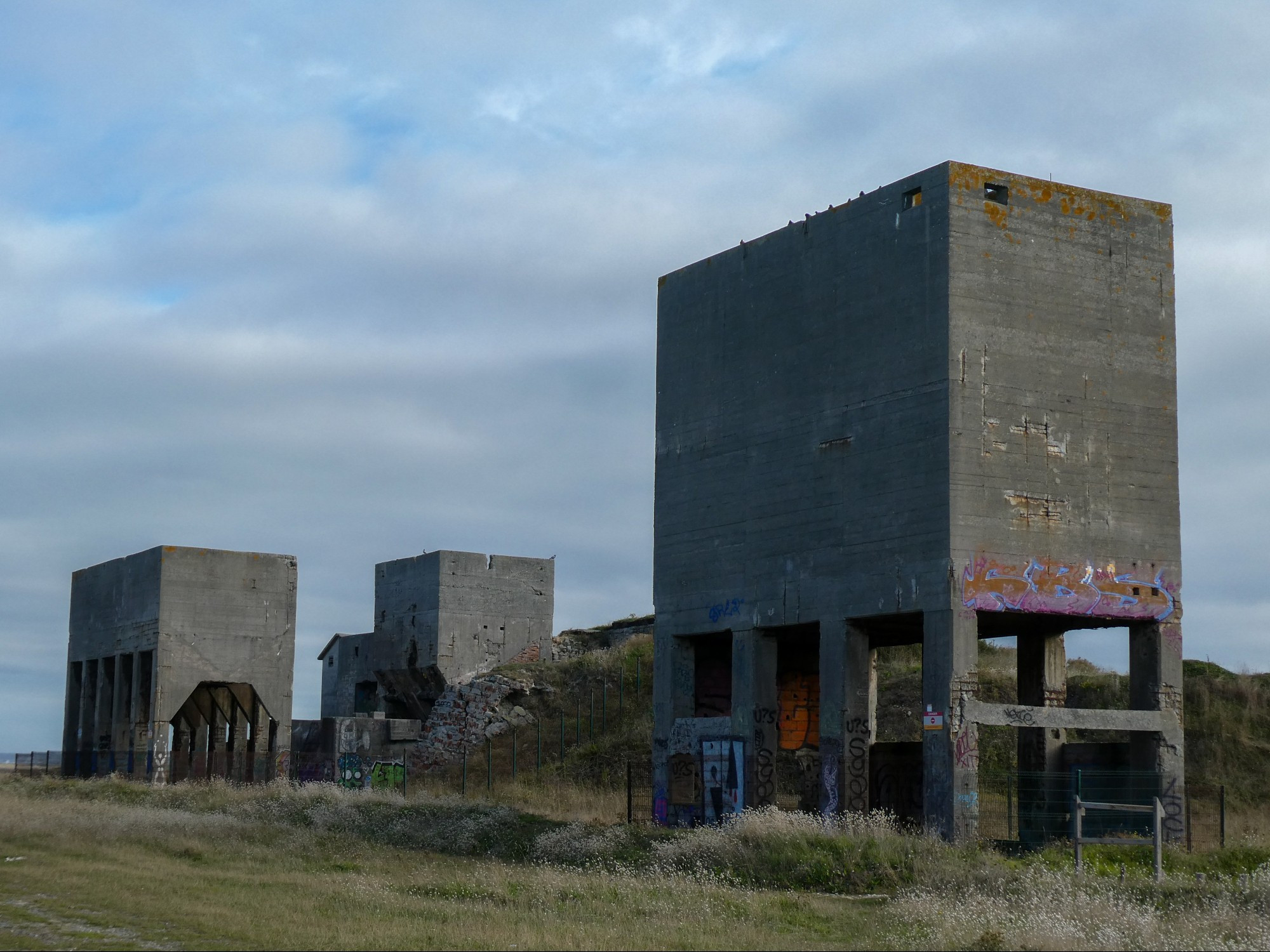 Graffitied concrete gravel hoppers over what was the rail spur to the site.