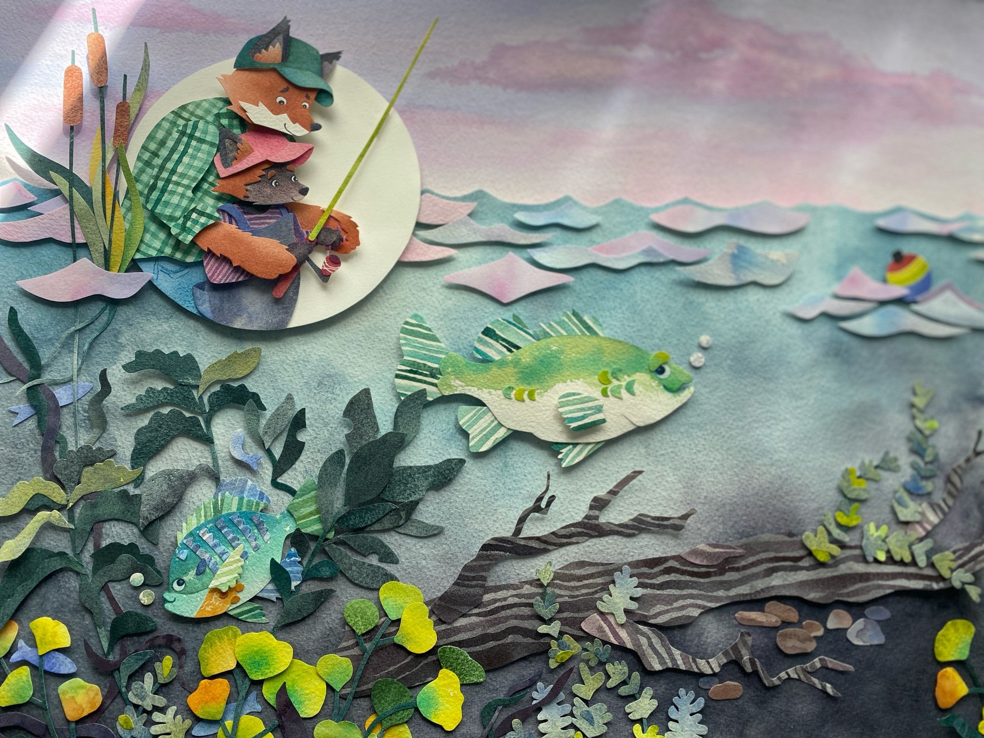 Photo of a children’s book illustration created with watercolor and cut paper collage. Two foxes are pictured, fishing in a colorful pond with two fishes smiling up at them.