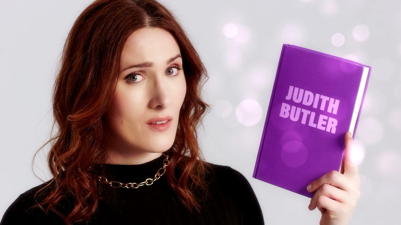 Abi holding a book labelled ‘Judith Butler’ looking curious