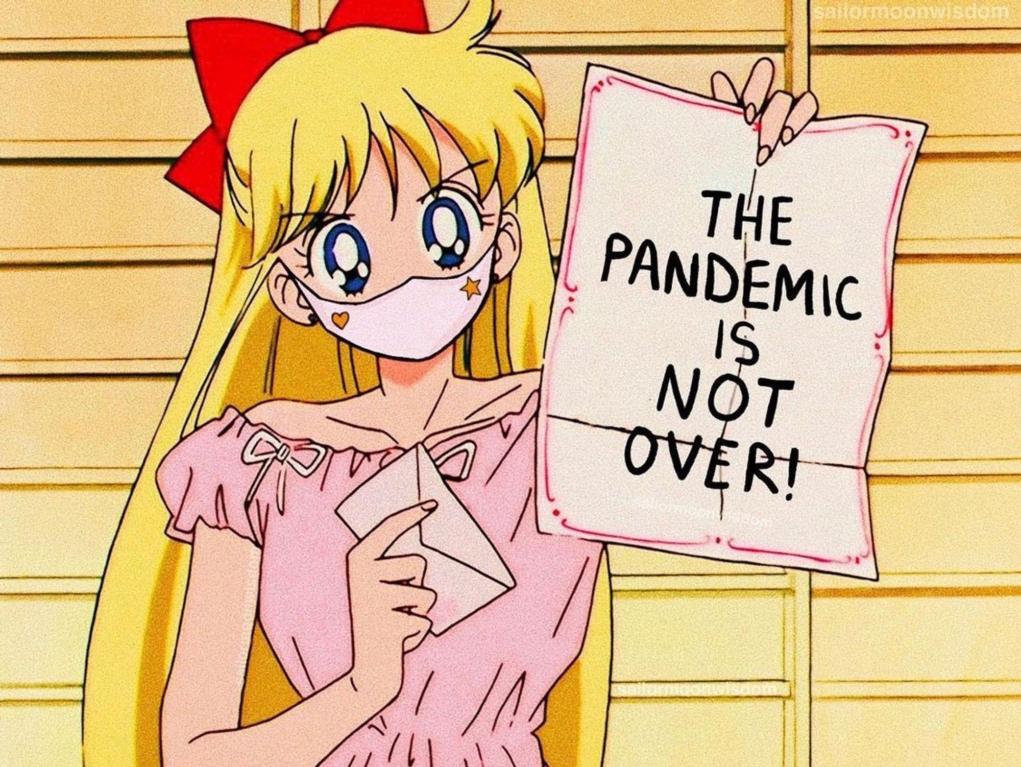 Minako Aino, aka Sailor Venus from Sailor Moon wearing a mask and holding a letter that reads, “THE PANDEMIC IS NOT OVER!”