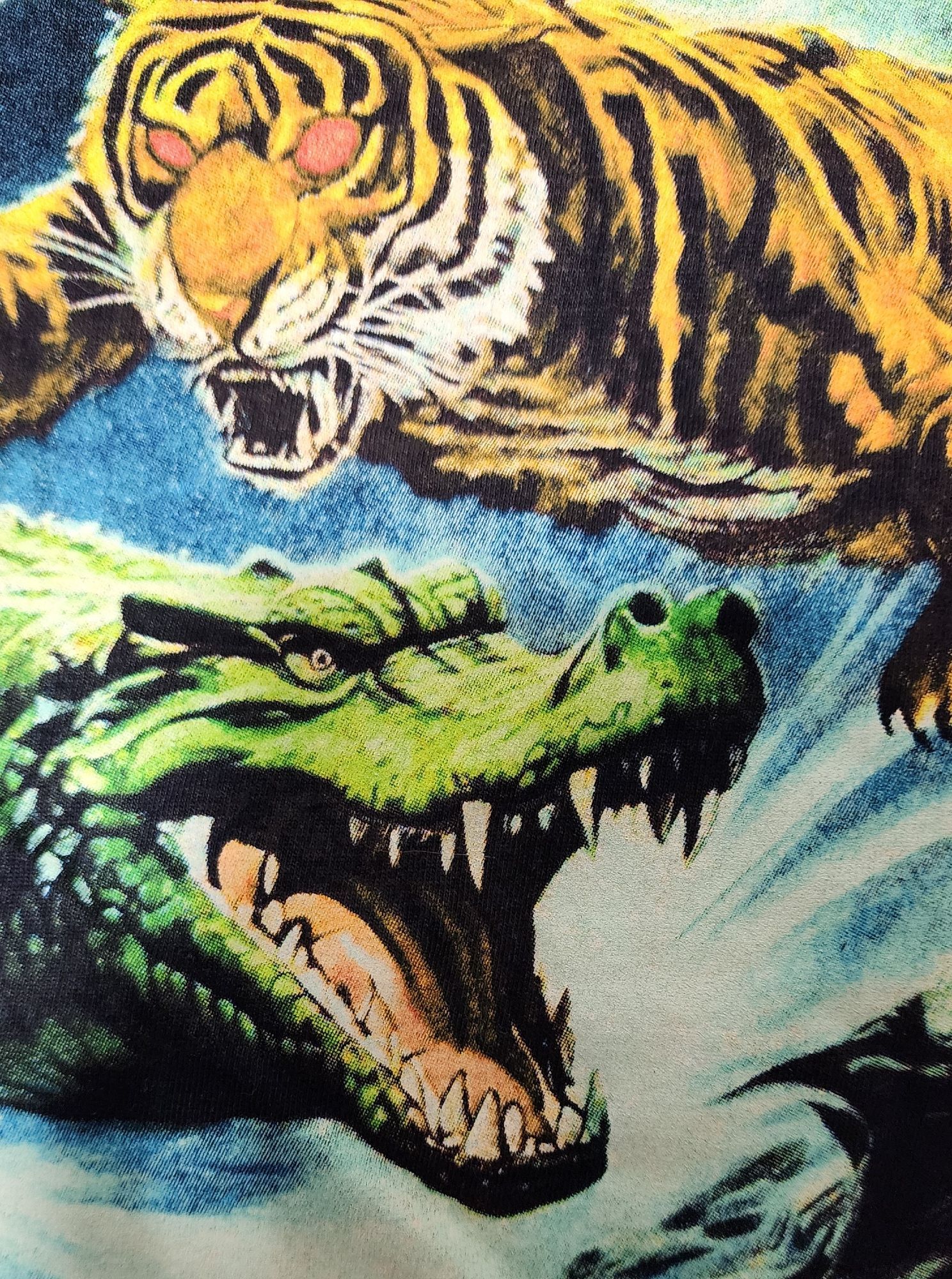 Detail of the shirt, showing the faces of the gator and tiger. The aligator's teeth are nebulous, overlap in strange ways and the eyes and nosptils are uneven. The tiger has similarly strange teeth.