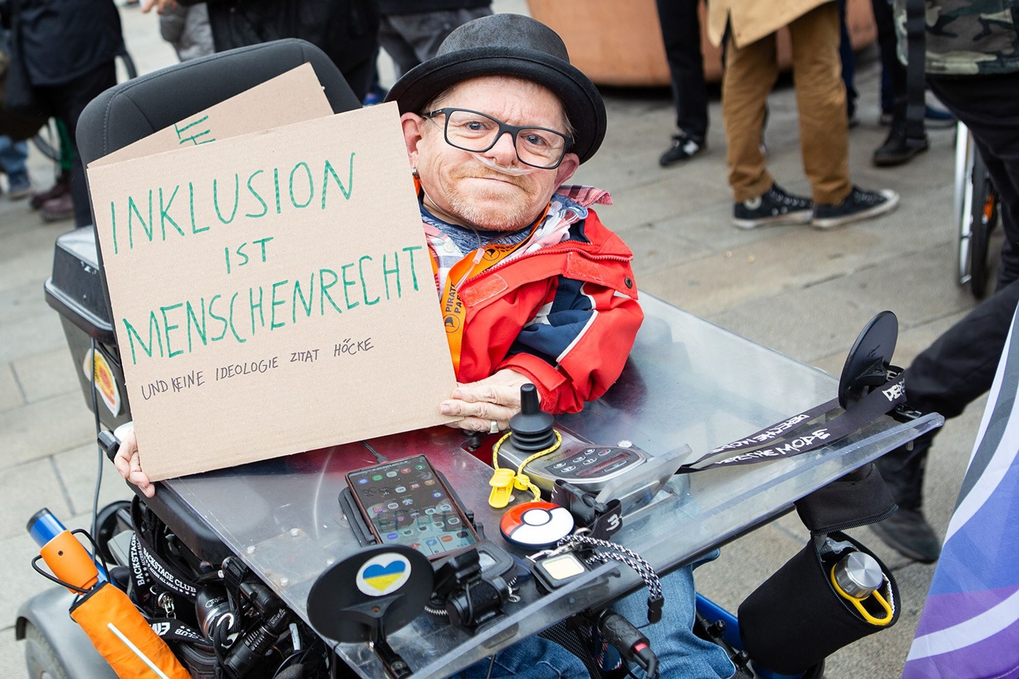 Demo gegen Rechts, zu sehen ist der in einem Spezialrollstuhl sitzende und in die Kamera lächelnde Erfurter Politiker und Aktivist Markus Walloschek mit einem Plakat, auf dem steht "Inklusion ist Menschrecht und keine Ideologie Zitat Höcke"