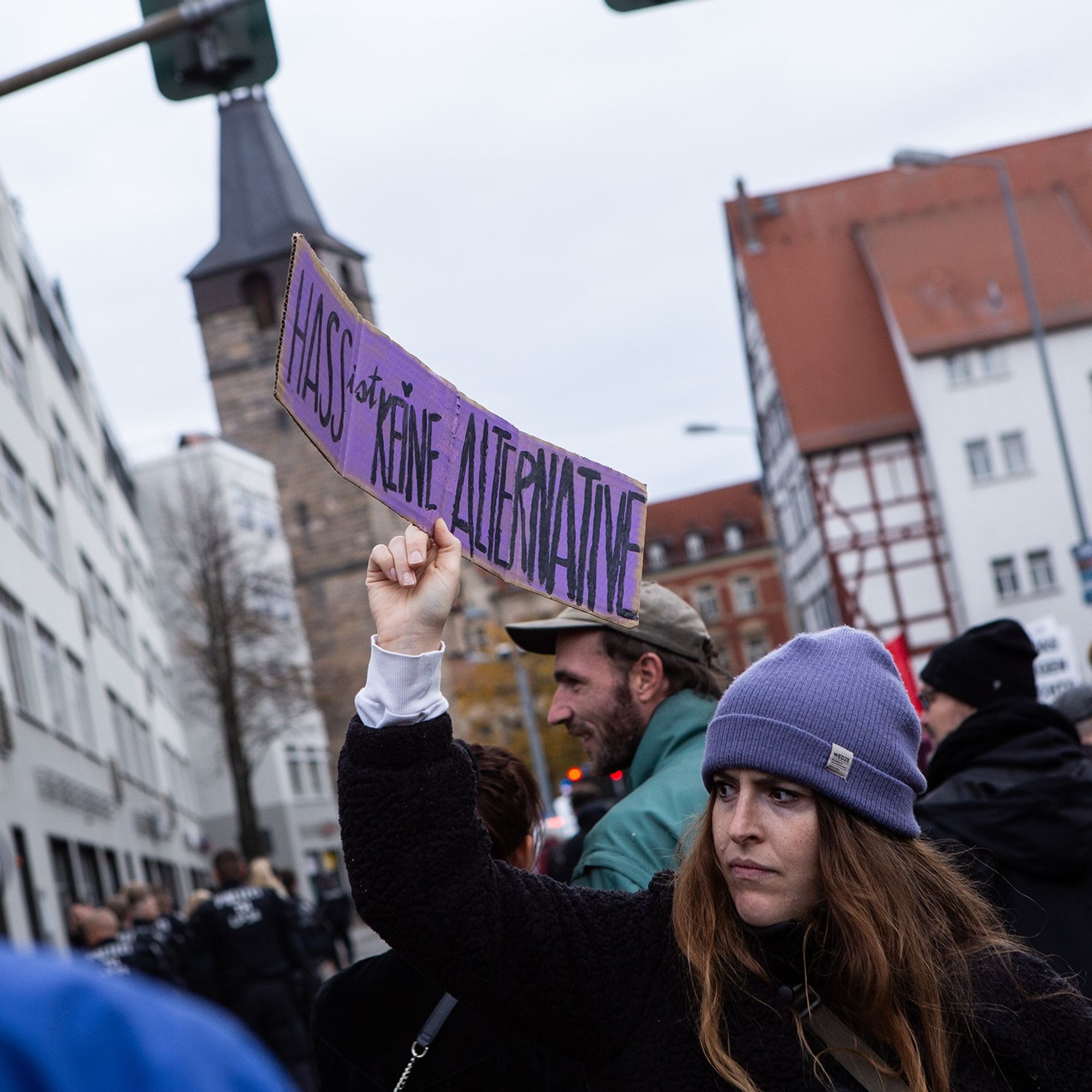 Demo gegen Rechts, im Demozug. Eine Frau mit langen braunen Haaren und lila Mütze hält ein lila Schild hoch "Hass ist keine Alternative"