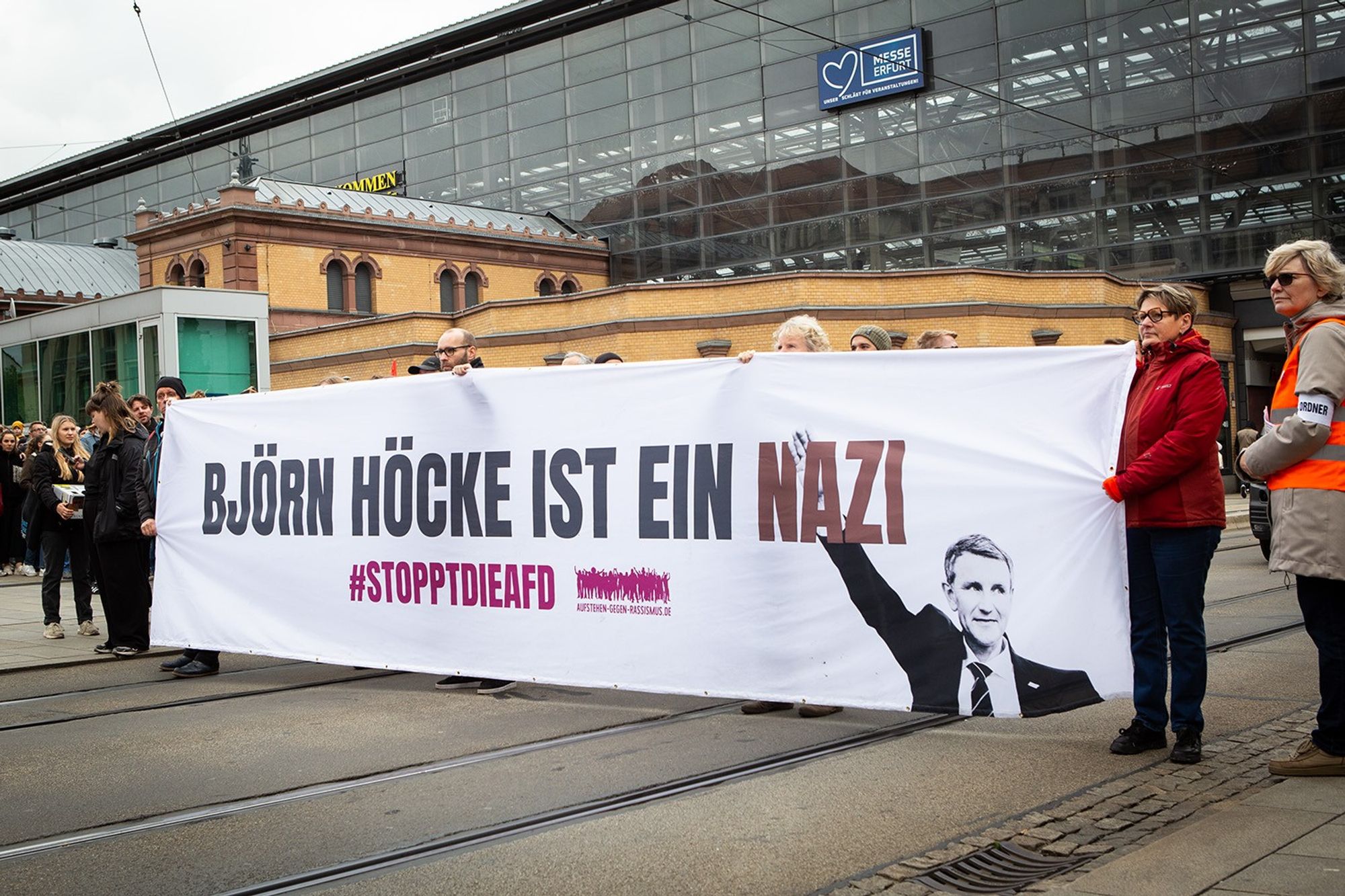 Demo gegen Rechts, 2. Teil der Demo vor dem Hauptbahnhof. Kaum sichtbare Menschen halten ein großes weißes Plakat auf dem steht "Björn Höcke ist ein Nazi #stopptdieAFD"