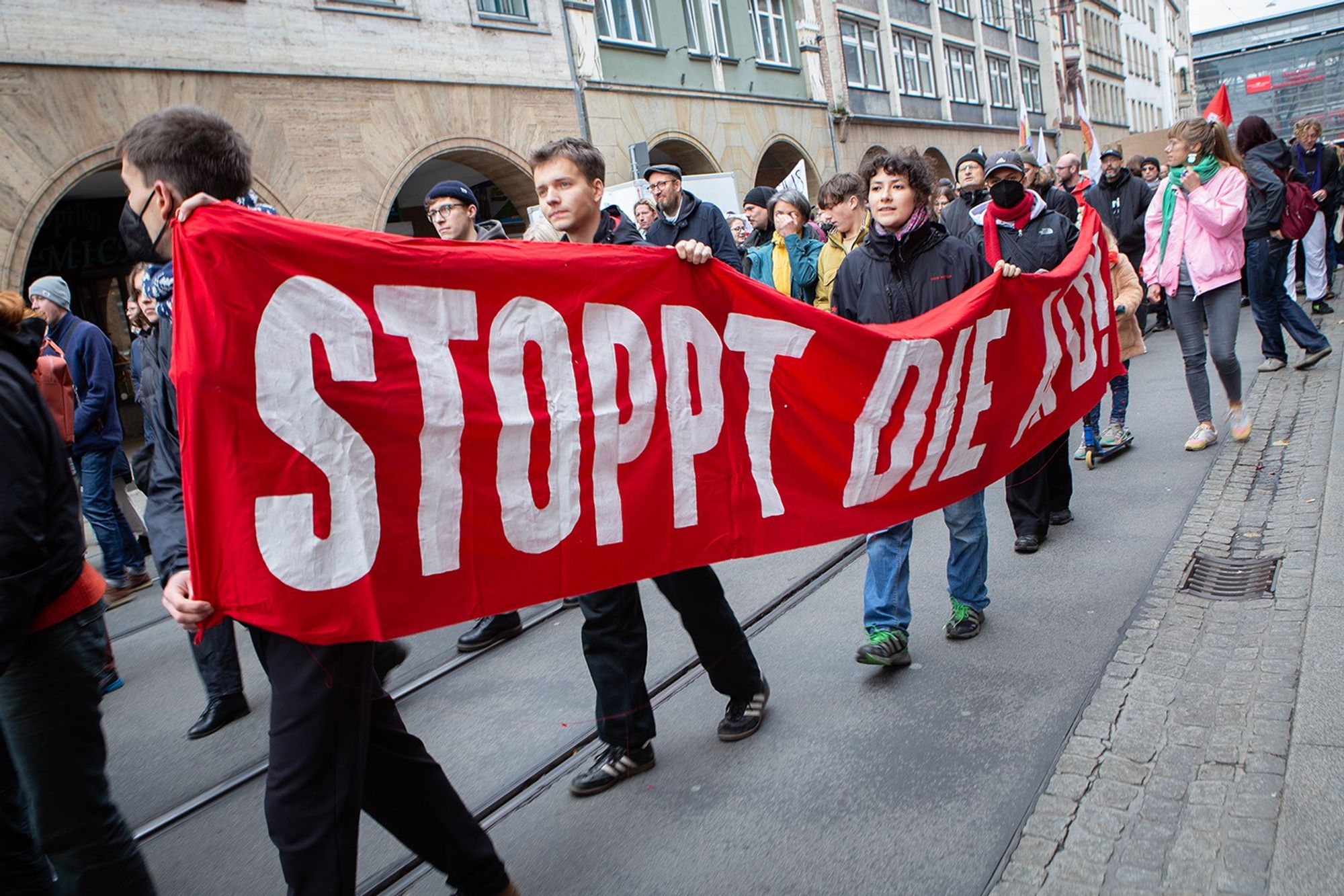 Demo gegen Rechts, Demozug. Junge Menschen halten ein großes rotes Transparent "Stoppt die AFD"