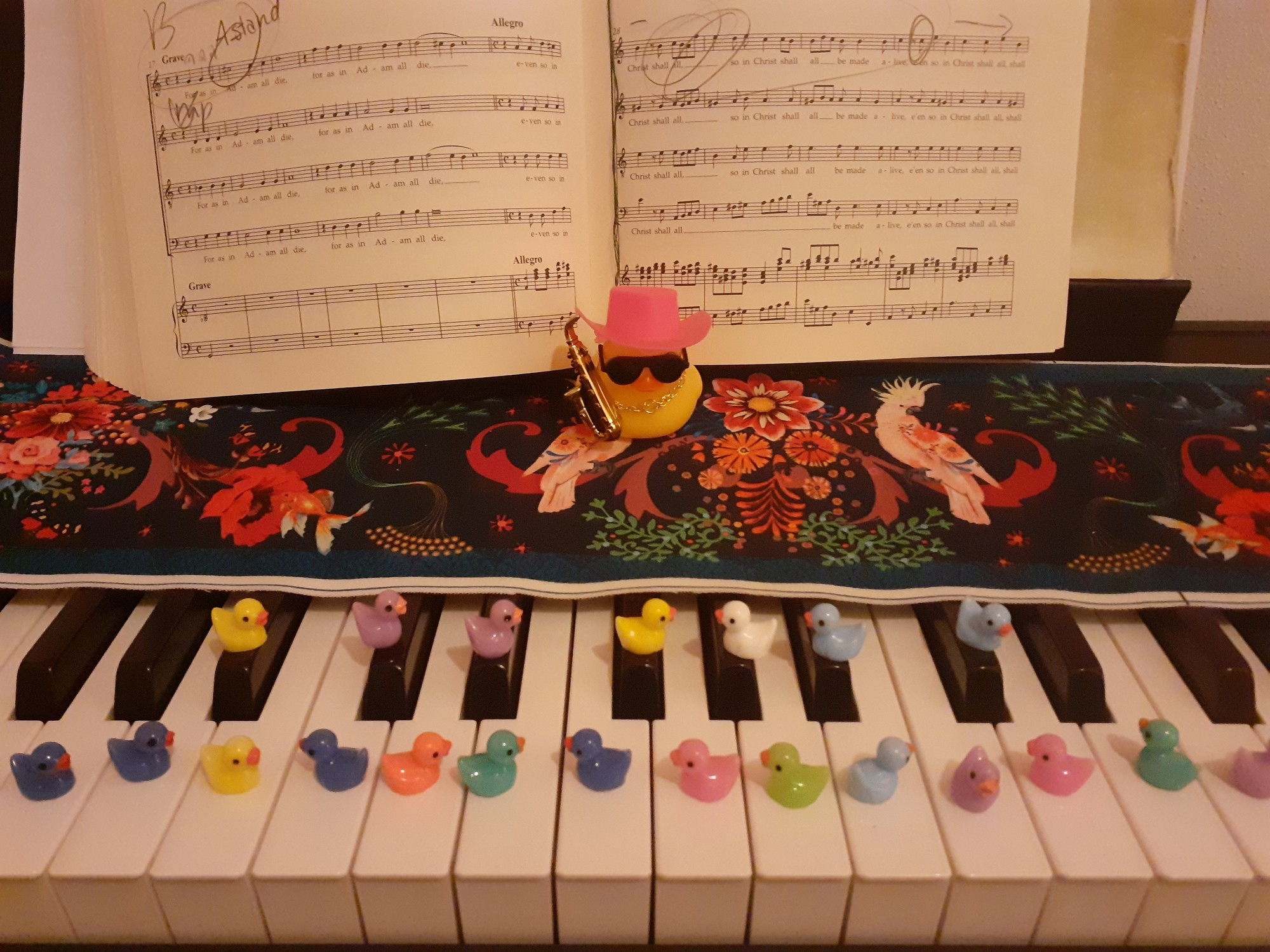 Tiny bathtub ducks on a piano, on each key of the piano, 1 larger bathtub ducks with saxophone just before the sheet music