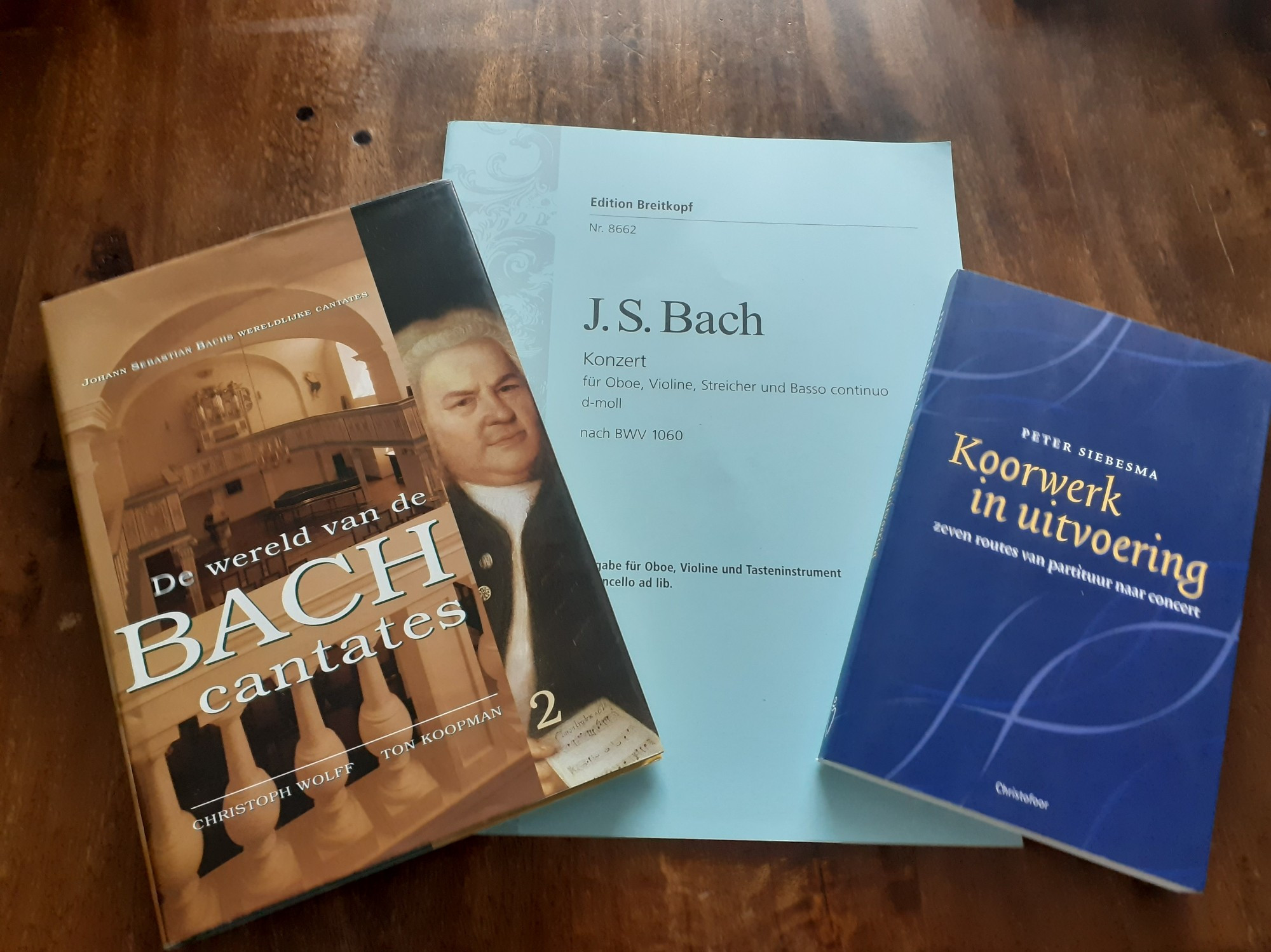 3 books on a table: 1 book with sheet music of Bach, 1 book about Bach cantatas and 1 book about how choirs functioning