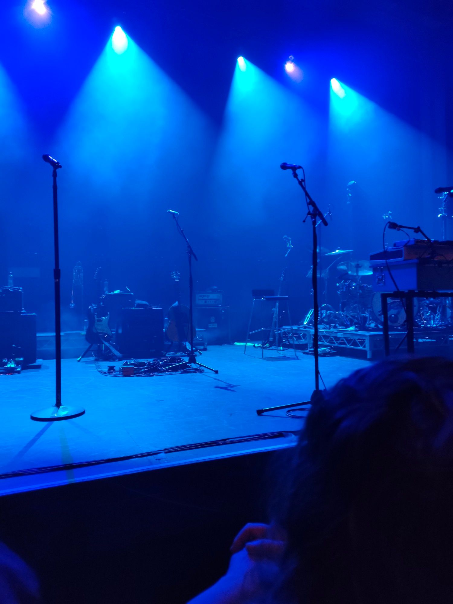 An empty stage set up for a concert, taken from the second row of people standing at the front