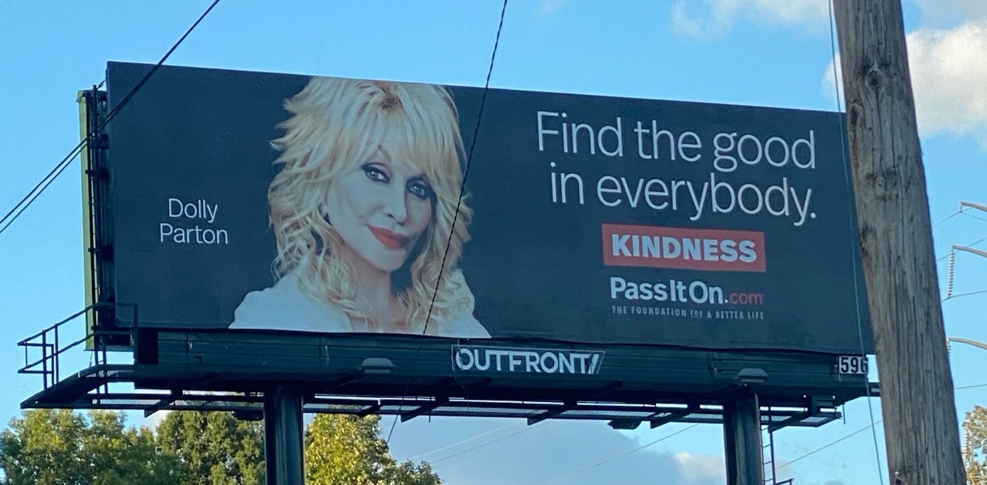 Dolly billboard with her photo and text “find the good in everybody. Kindness. pass it on dot com”