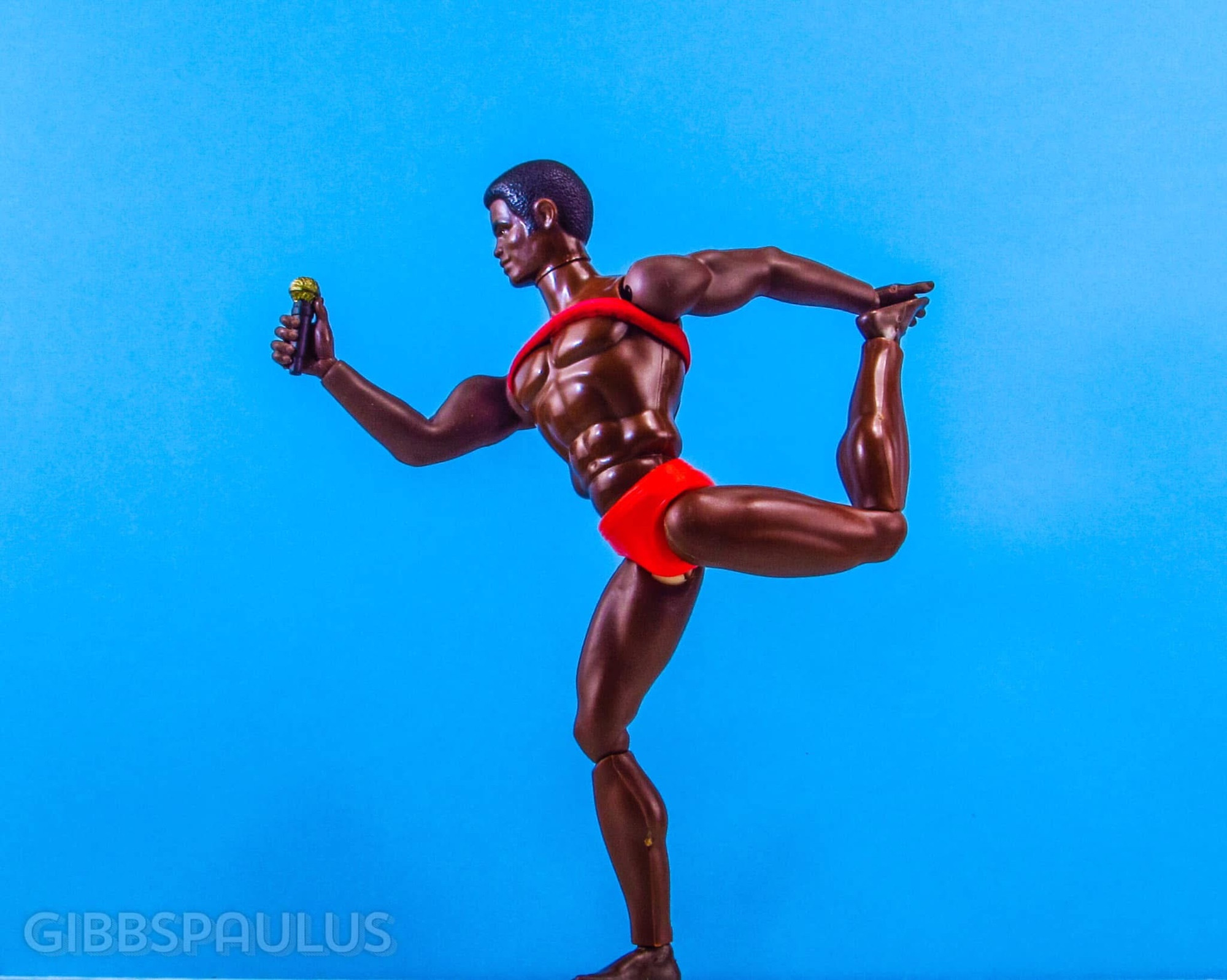A black male doll in a dramatically balanced pose