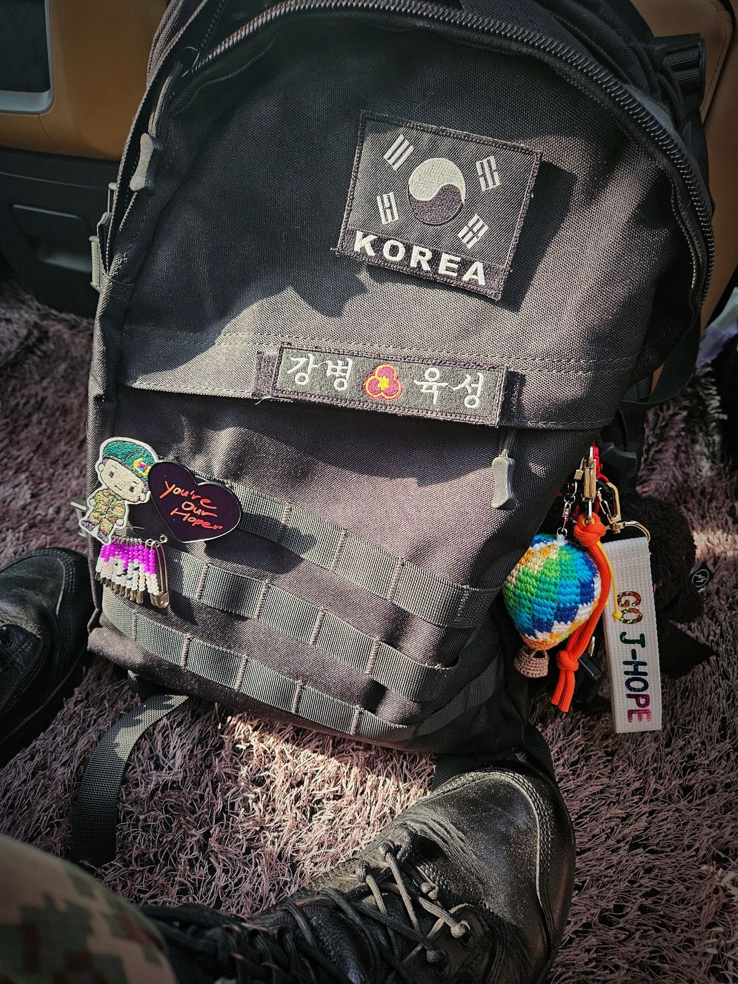 Black backpack with a Korean flag and lots of bits and bobs including a crochet of the Young Forever hot air balloon