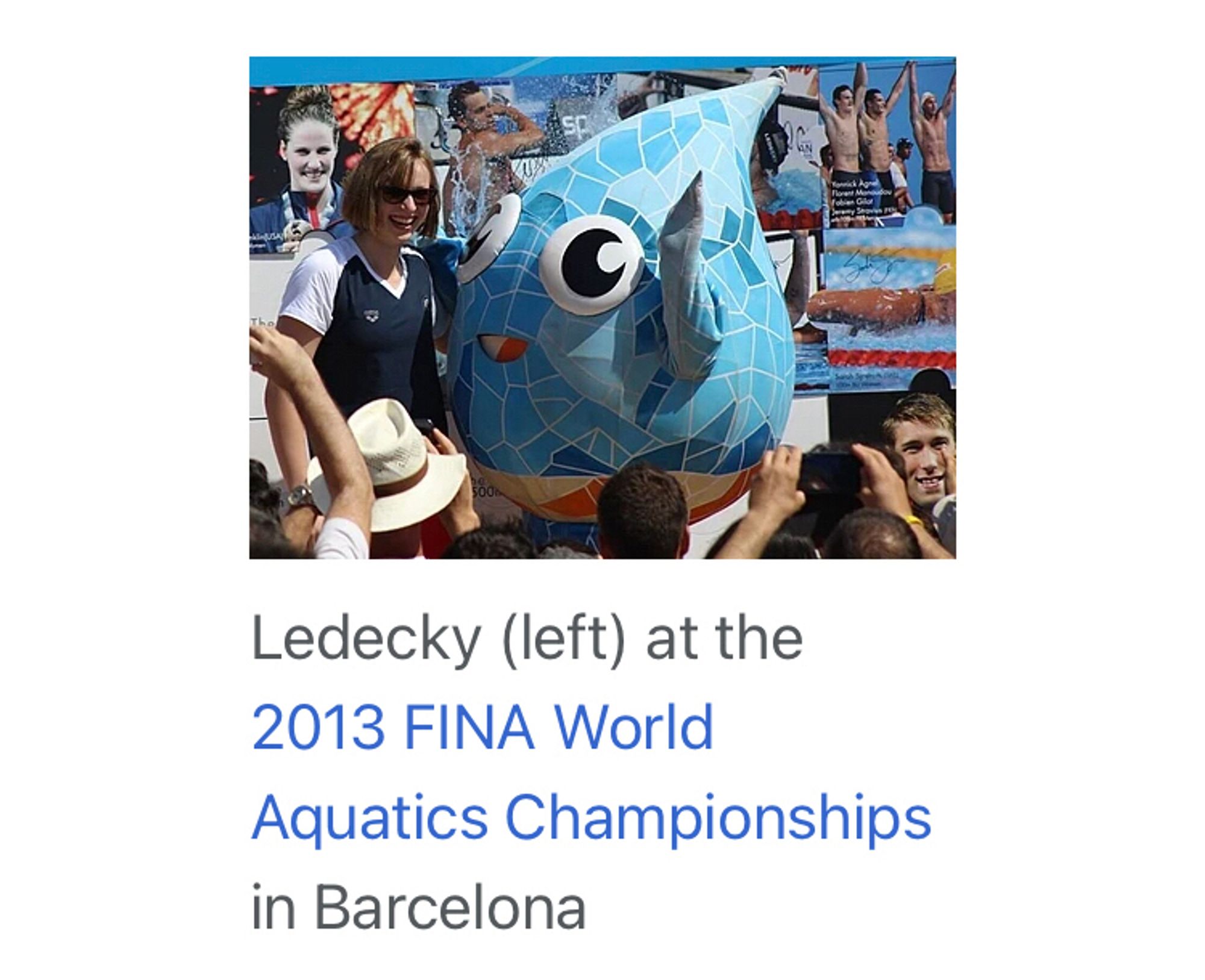 A picture of swimming god Katie Ledecky next to a water drop mascot. 

The caption reads: Ledecky (left) at the 2013 FINA World Aquatics Championships in Barcelona.