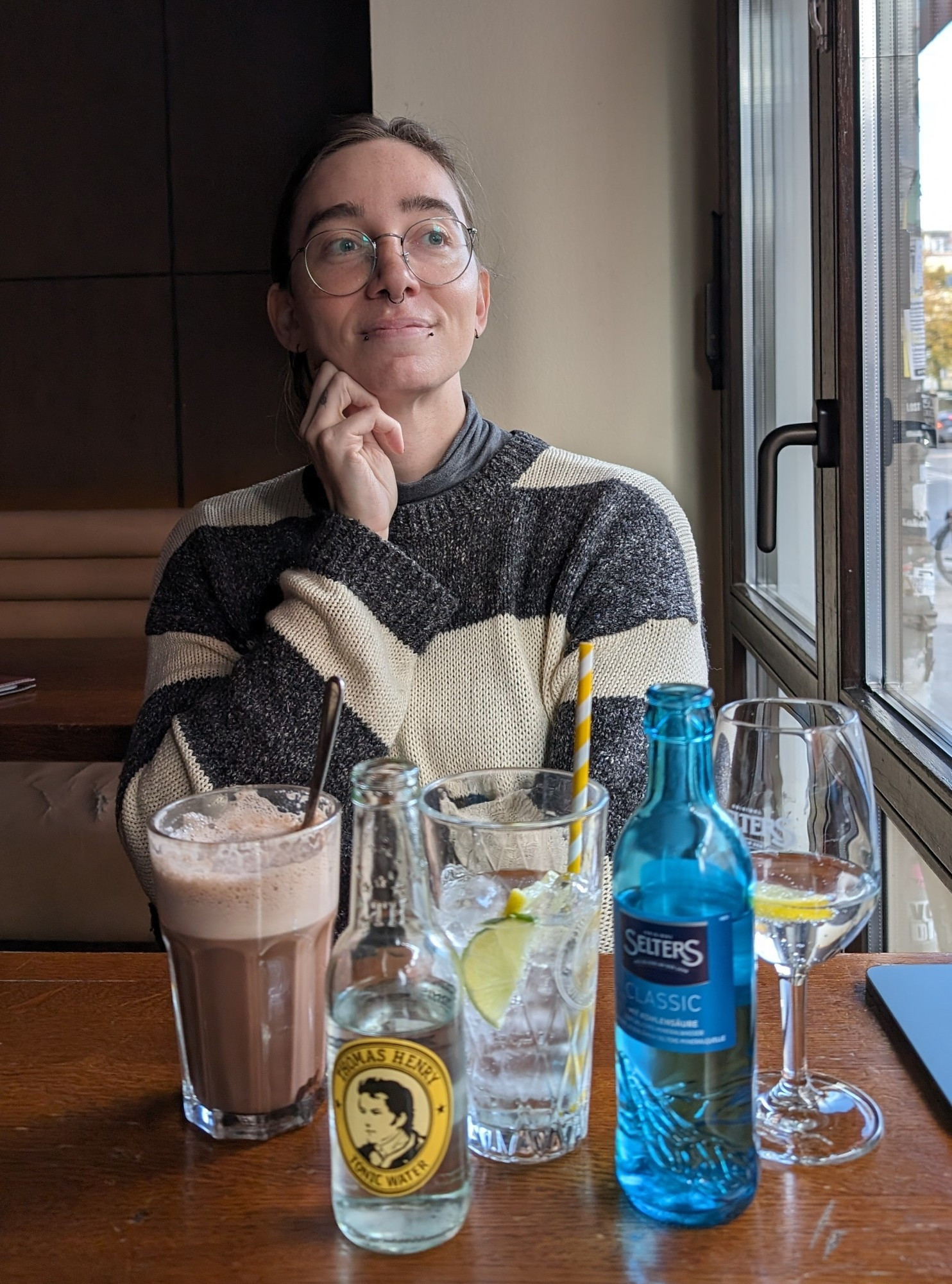 Vee sitting in front of five containers of liquid: hot chocolate, gin & tonic, and sparkling water