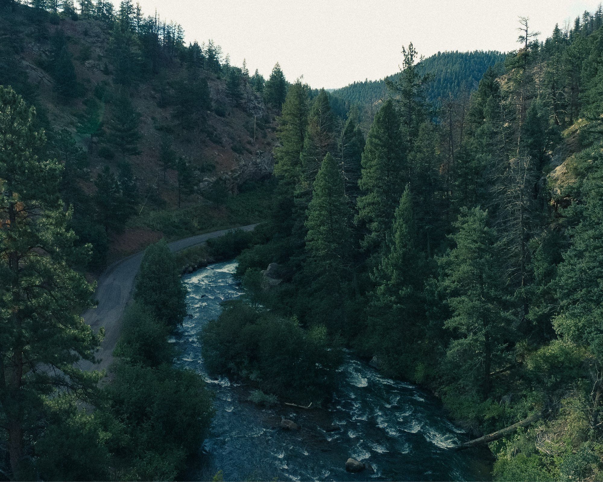 Drone photo over a river, at an even higher angle, along the road