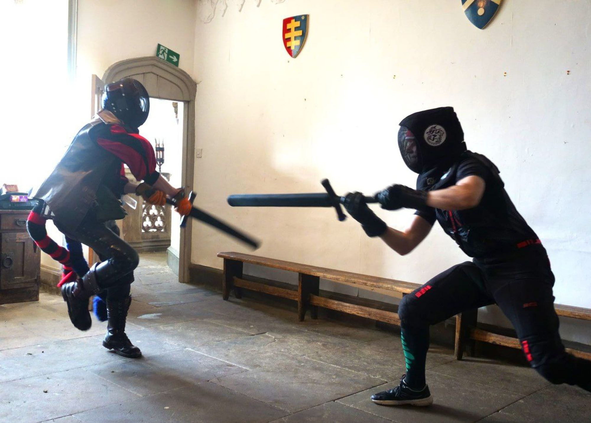 a couple wearing protective gear fencing using foam boffer swords