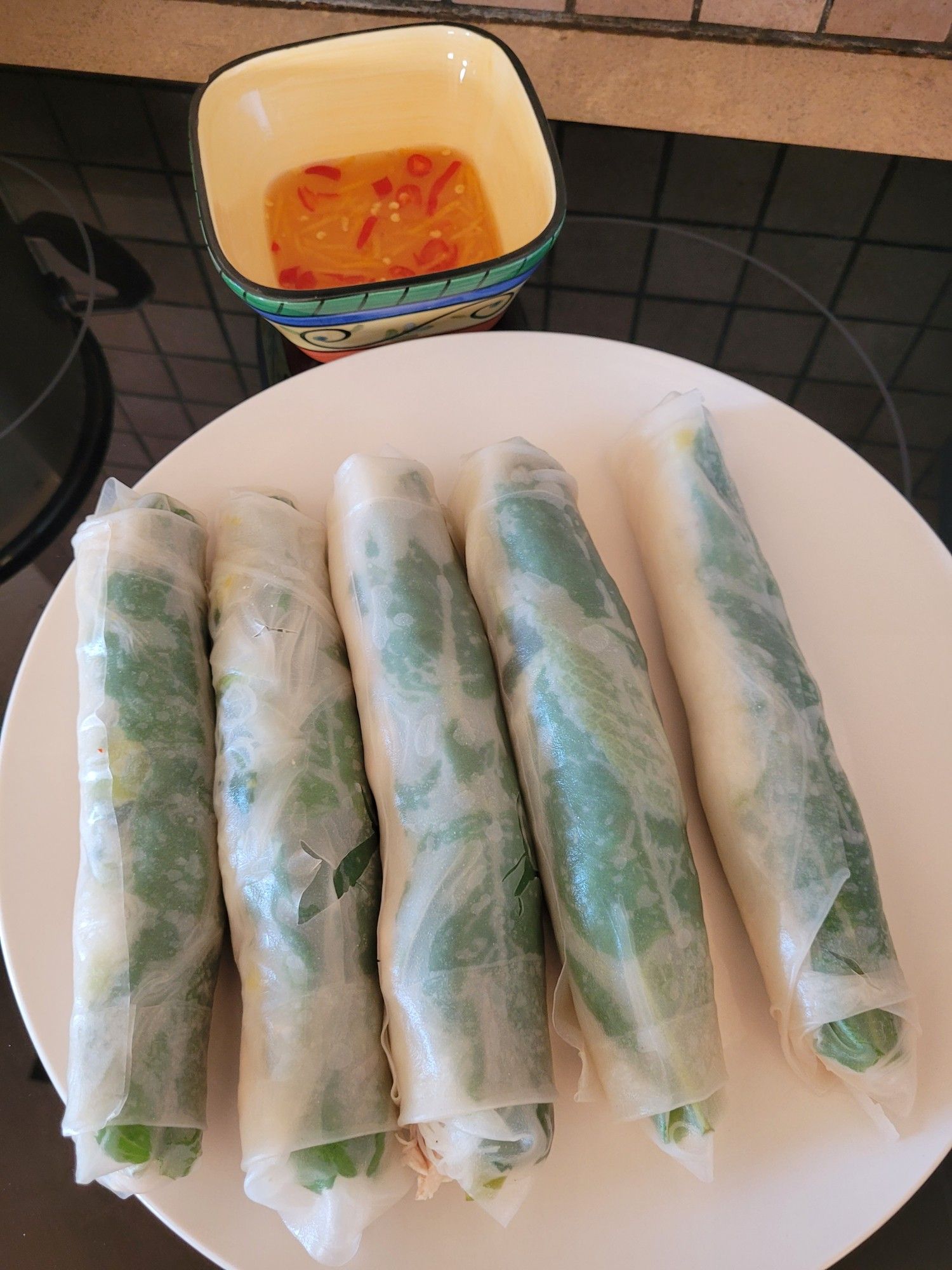 Dinner as described: five fresh rice rolls on a round white plate, and on the side the dipping sauce in a square ramekin.