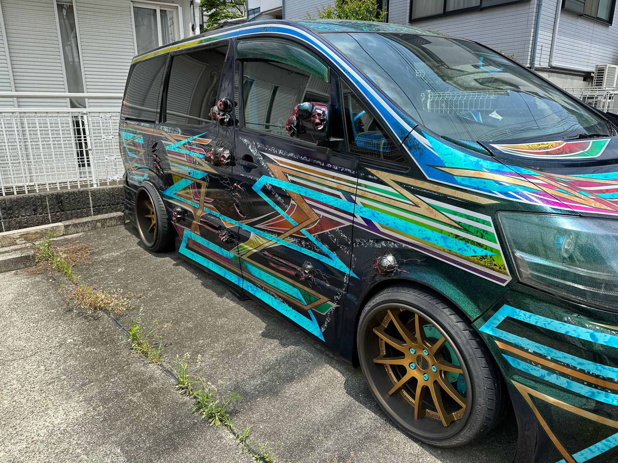 Picture from the side of same car, skulls embedded in body of car at several places. The car also has been lowered, so good luck getting over any speed bumps. Do they even have speed bumps in Japan? I can not recall ever having seen any. By the way, the body of the bar has lots of colourful jaggedy lines and patterns.