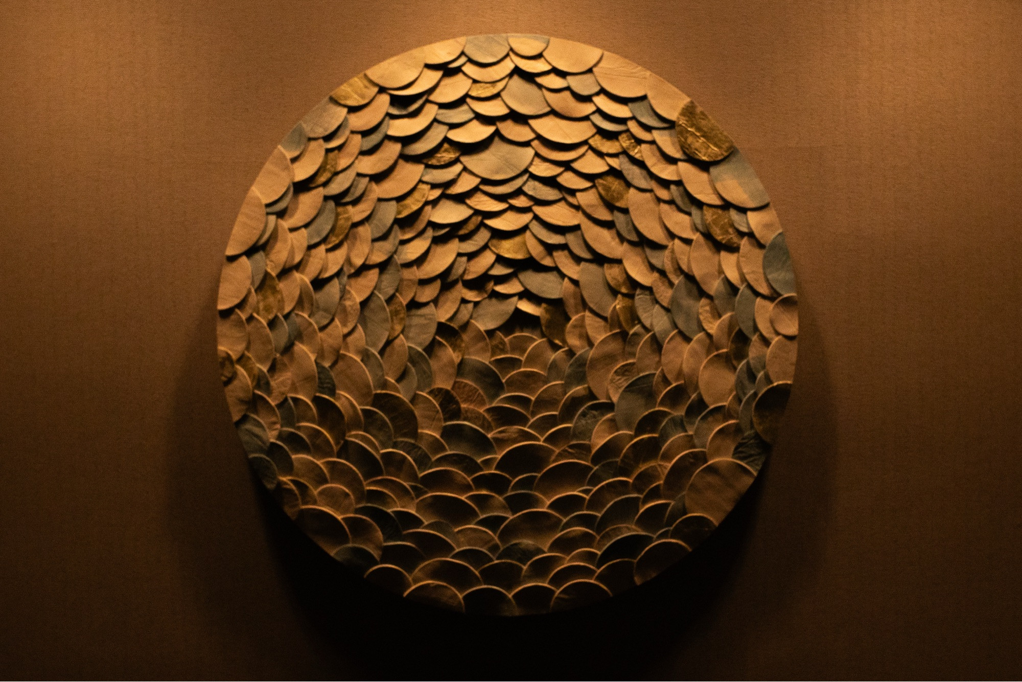 A circular wall decoration at a hotel. Textured with overlapping circular pieces of wood.