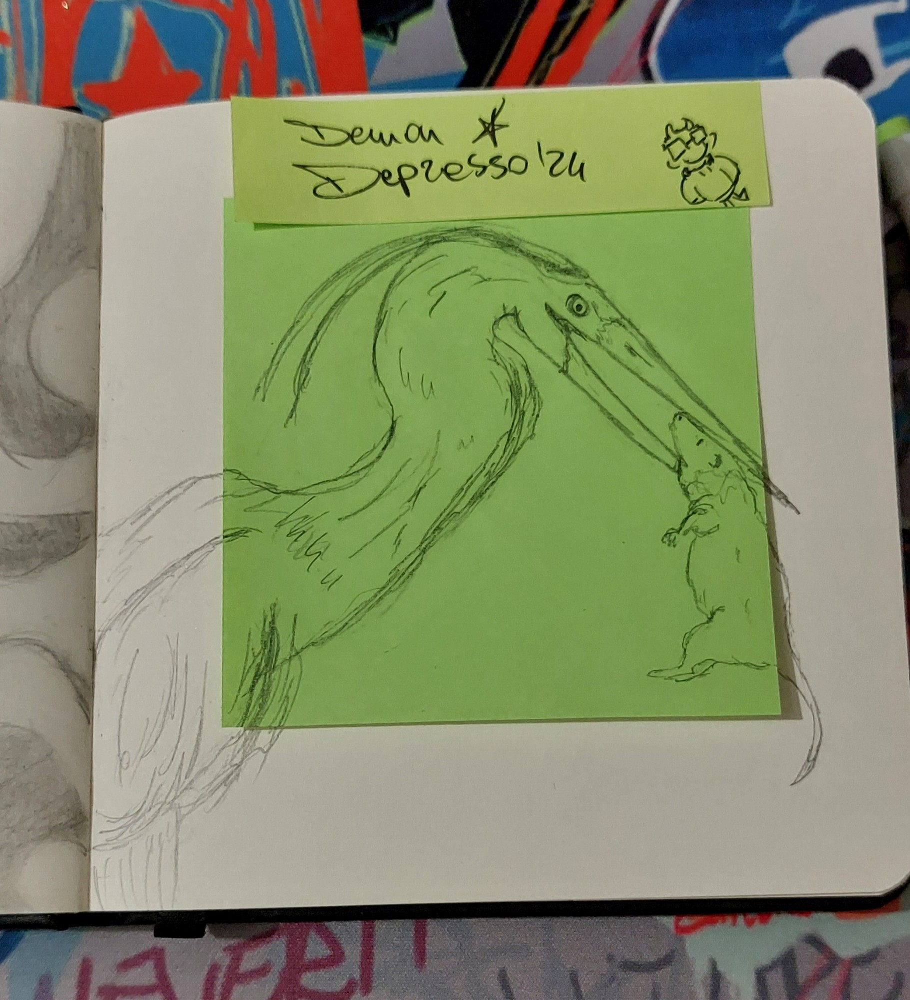 Photo of a square sketchbook page, it's off-white and in the center there's a bright green sticky note. Over the sticky note and the rest of the page there's a sketch of an heron keeping their prey (a rat) in their beak. At the top of the page there is a smaller sticky note in pale green with my signature "Demon Depresso '24" and a little doodle of my sona in a corner. The background is a desk mat with a graffiti pattern