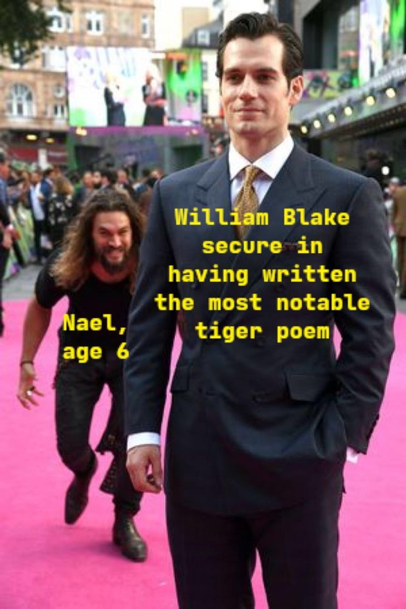 a meme of Henry Cavill posing handsomely on a red carpet, in a polished suit and styled hair, with the words “William Blake secure in having written the most notable tiger poem” superimposed on his image in yellow text. Behind Cavill you can see the actor Jason Momoa, more casually dressed, sneaking up in a crouch with a diabolical grin on his face. Superimposed on Momoa’s image: “Nael, age 6”.