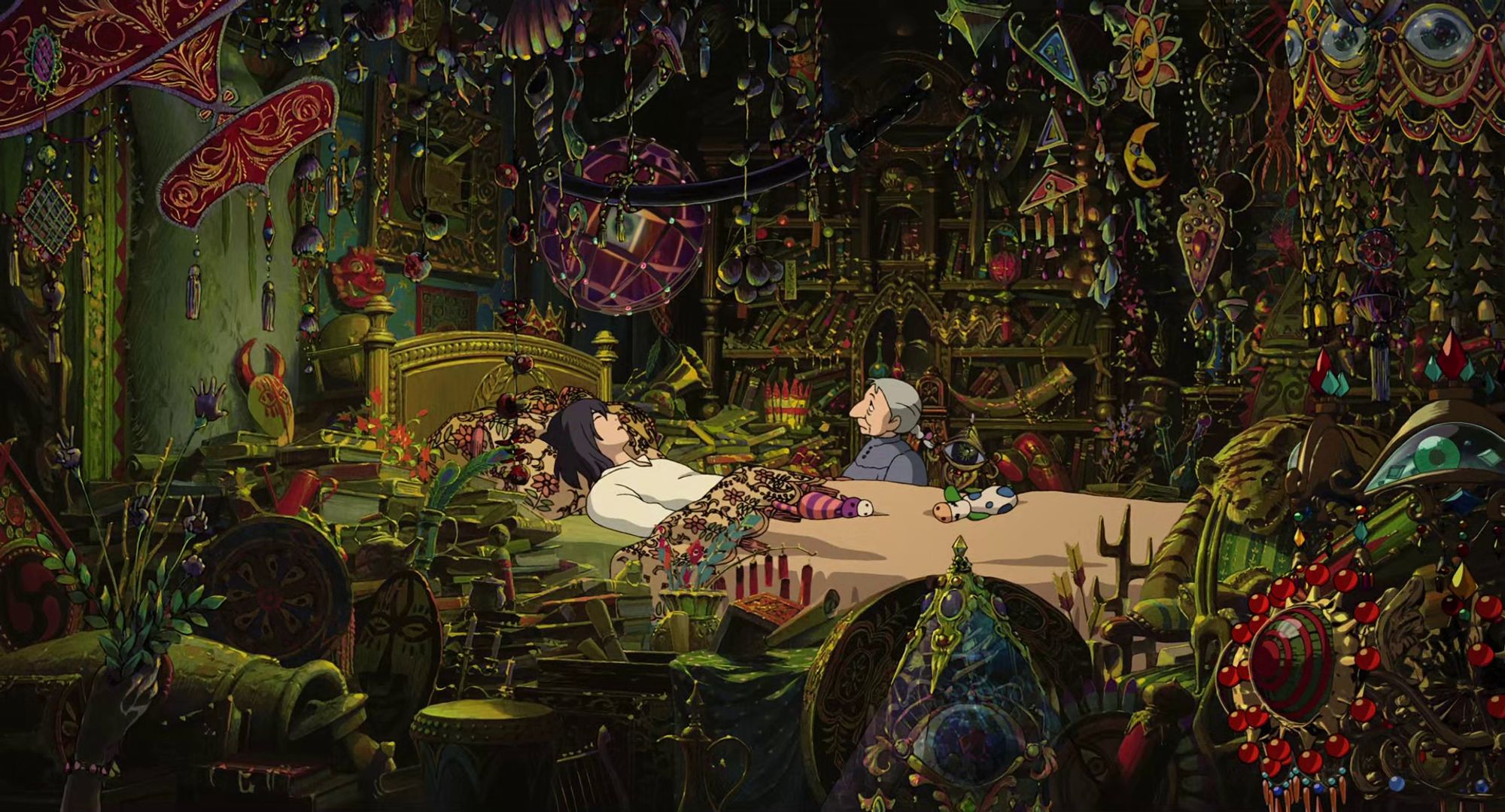 Screenshot from Howl's Moving Castle showing Howl's room absolutely stuffed to the gills with strange trinkets, jewelry and artifacts. Here we get a wide shot of the whole room, with Sophie sitting by Howl's side at the bed.