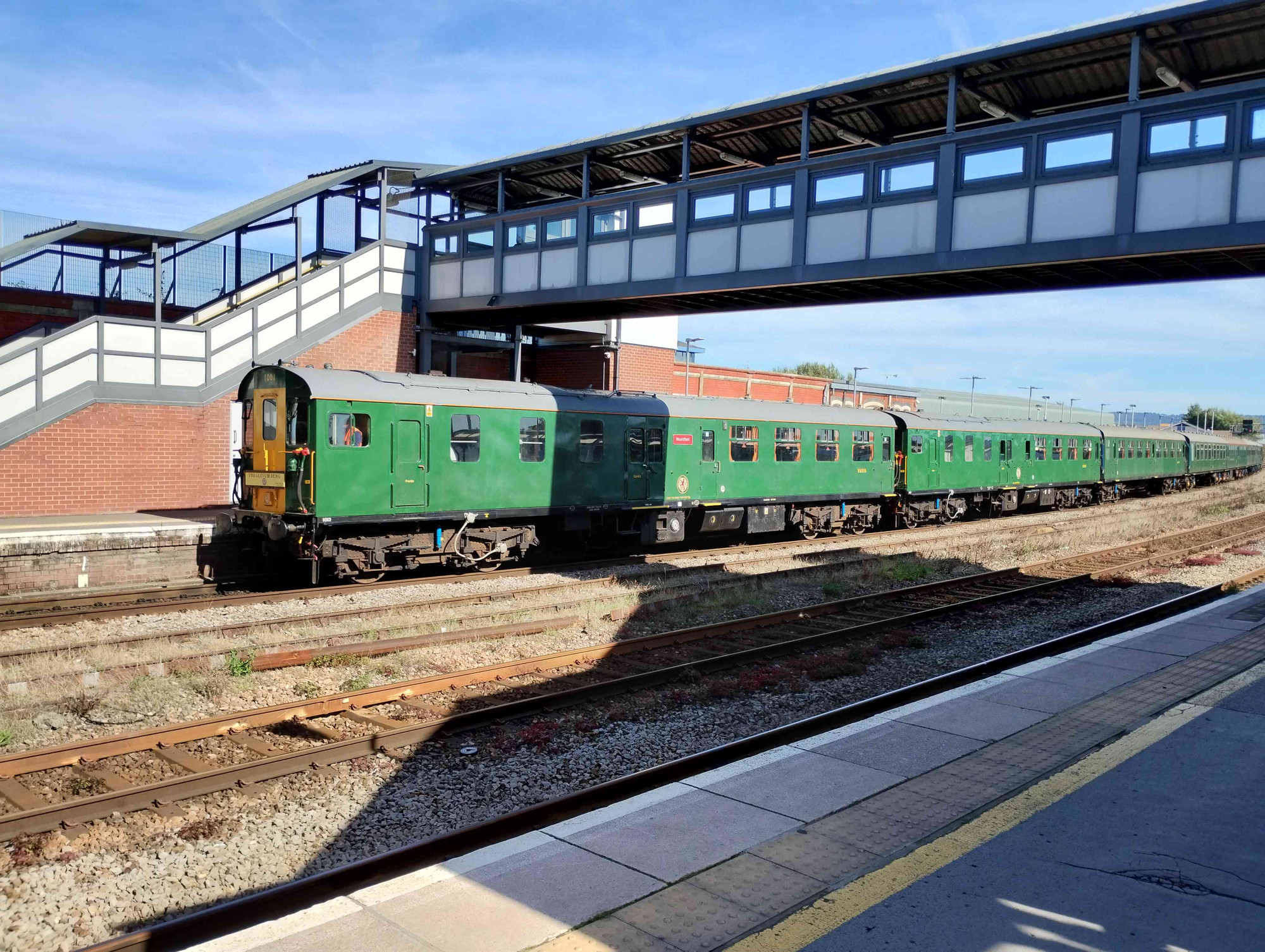 Green "Hastings" diesel electric multiple unit pulling ECS into Gloucester station, carrying a headboard from it's railtour to Cheltenham