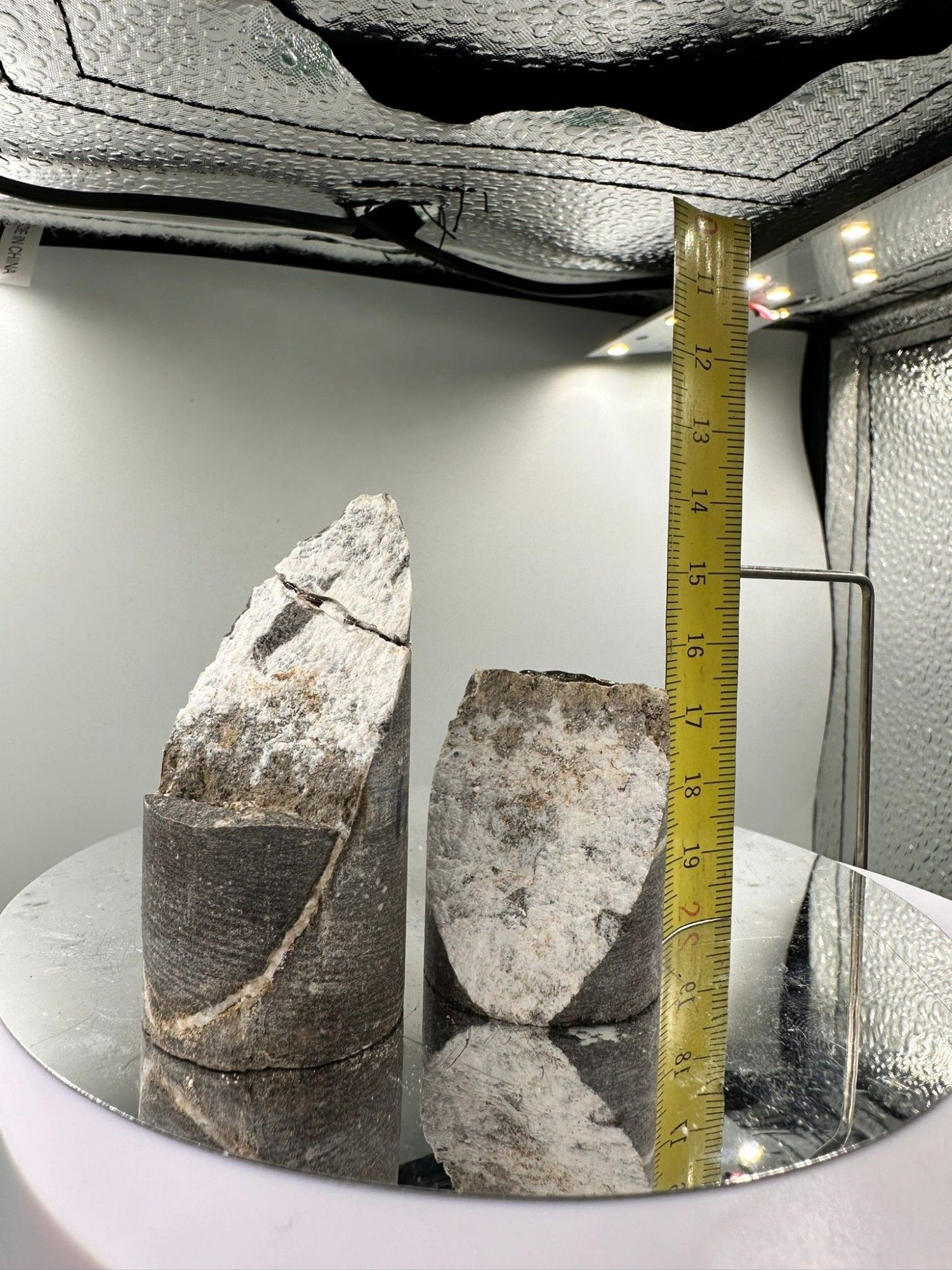 Fractured rock core in photo box, with centimeter scale showing cm-size