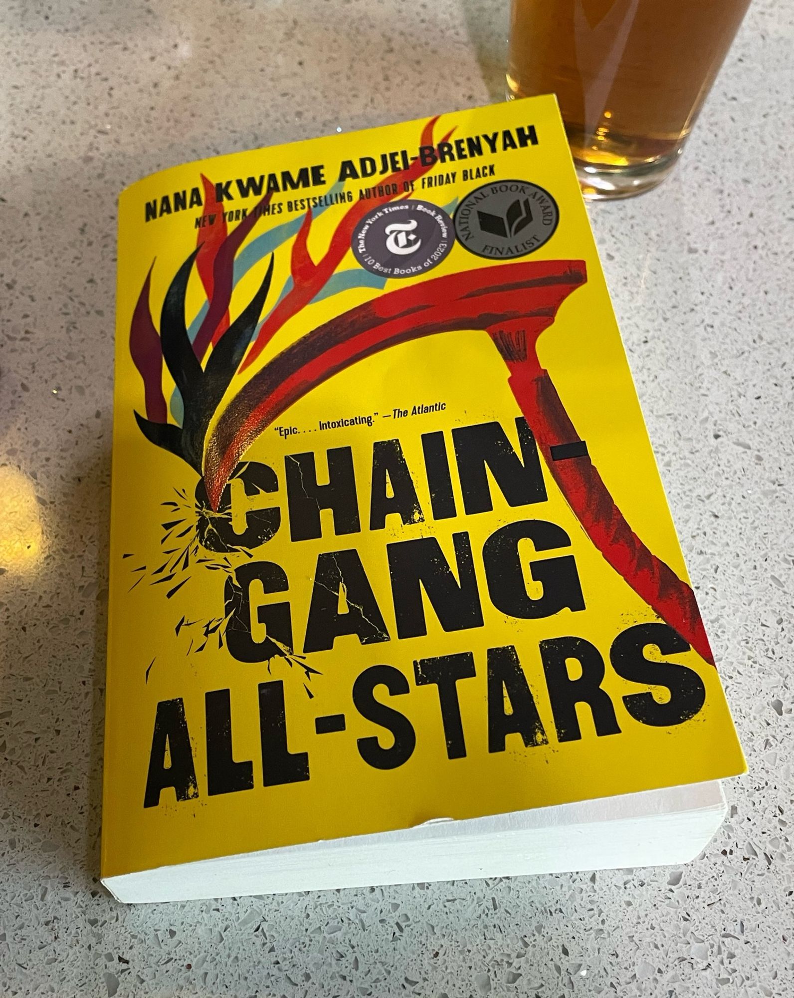 The book “Chain Gang All-Stars” sits on a counter next to a glass of iced tea.