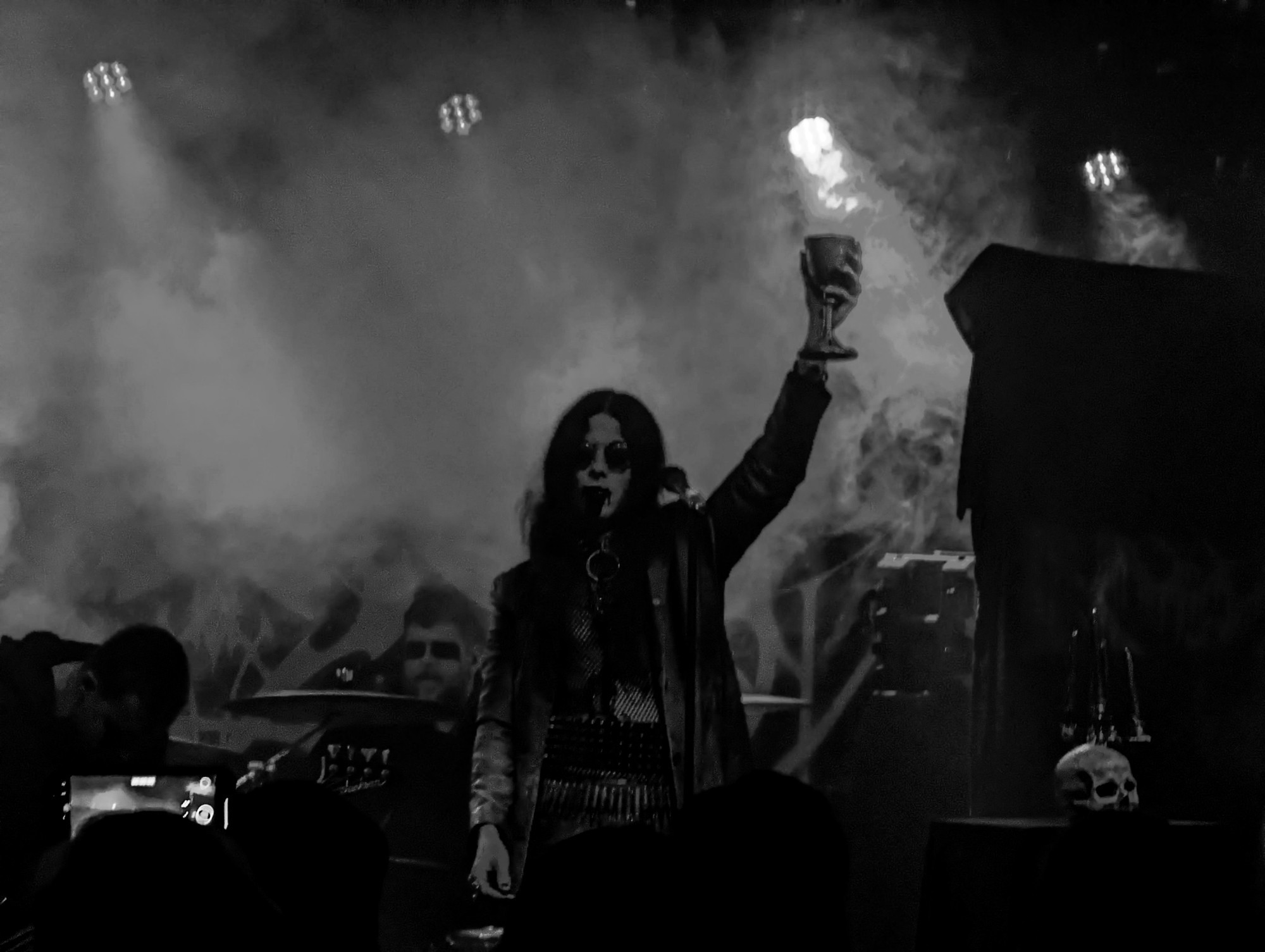 Grayscale photo of the vocalist for Worm holding a goblet of 'blood' aloft