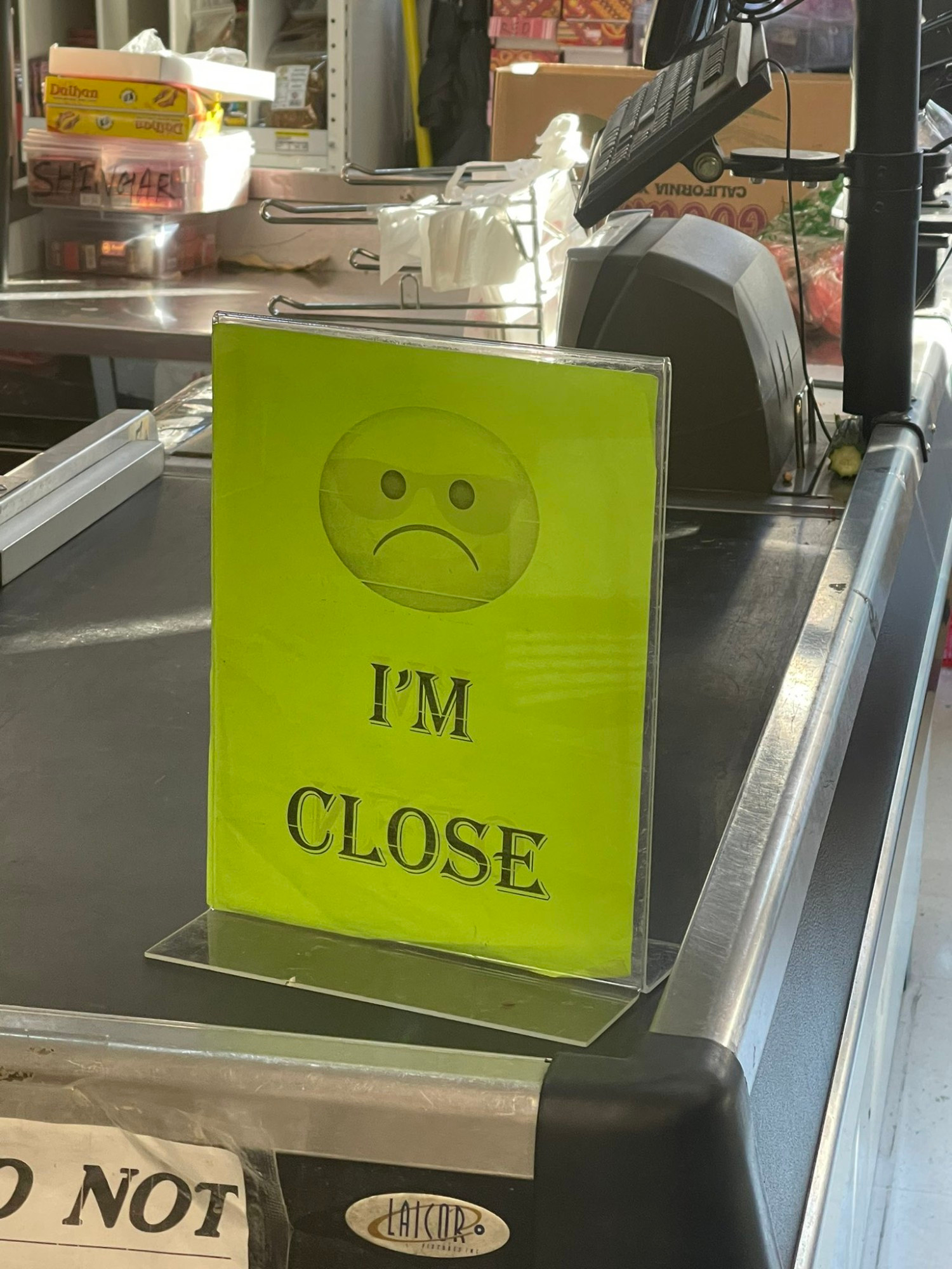 A green sign on a grocery store checkout with a sad face and the words I'm close underneath it