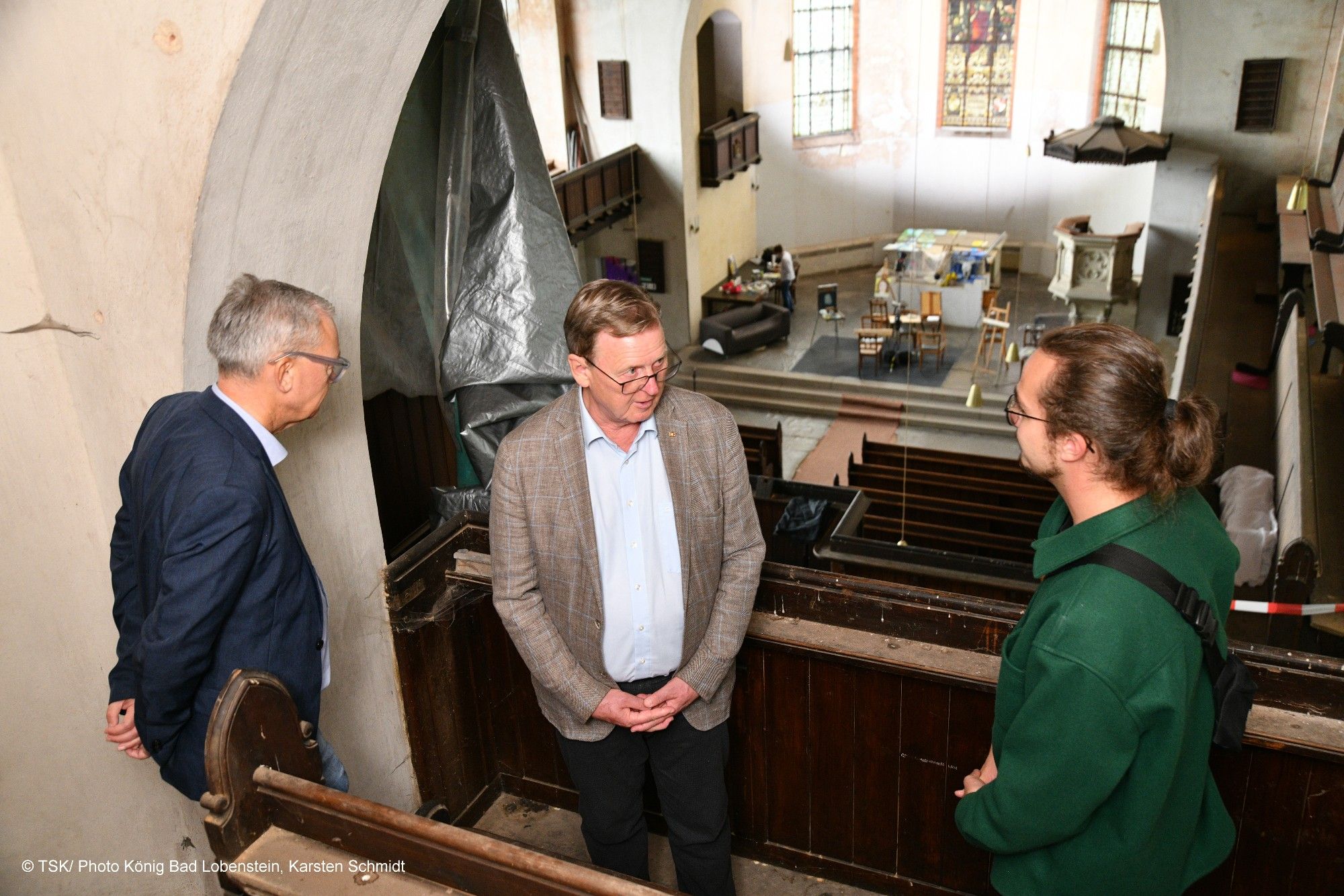 Ministerpräsident Bodo Ramelow im Gespräch mit einem der drei Gründer der Kultur-Kirche Greiz, Elric Simon Popp, und einem weiteren Mann. Sie stehen auf der Empore in der Kirche mit Blick zum Altar.