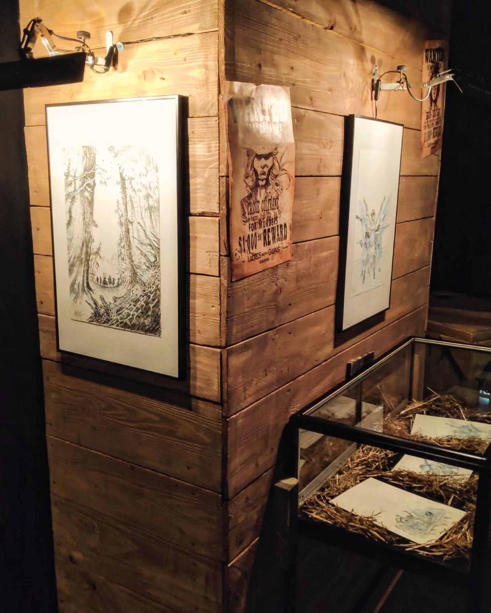 Belle ambiance de pénombre chaleureuse. Sur une palissade en bois, #expo de cadres avec des #planches originales de #BD. Dans la paille, des #croquis.