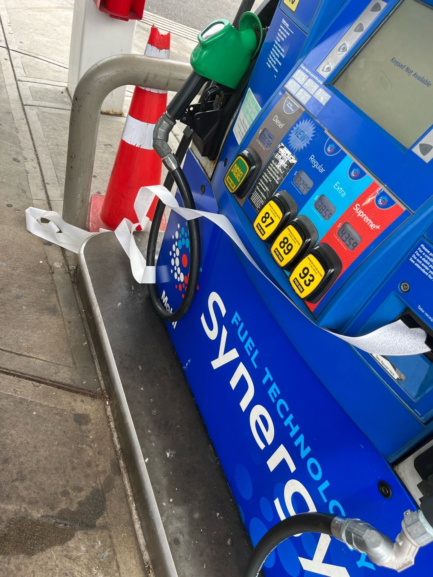 A gas station pump with a very long receipt coming out of it, trailing onto the ground