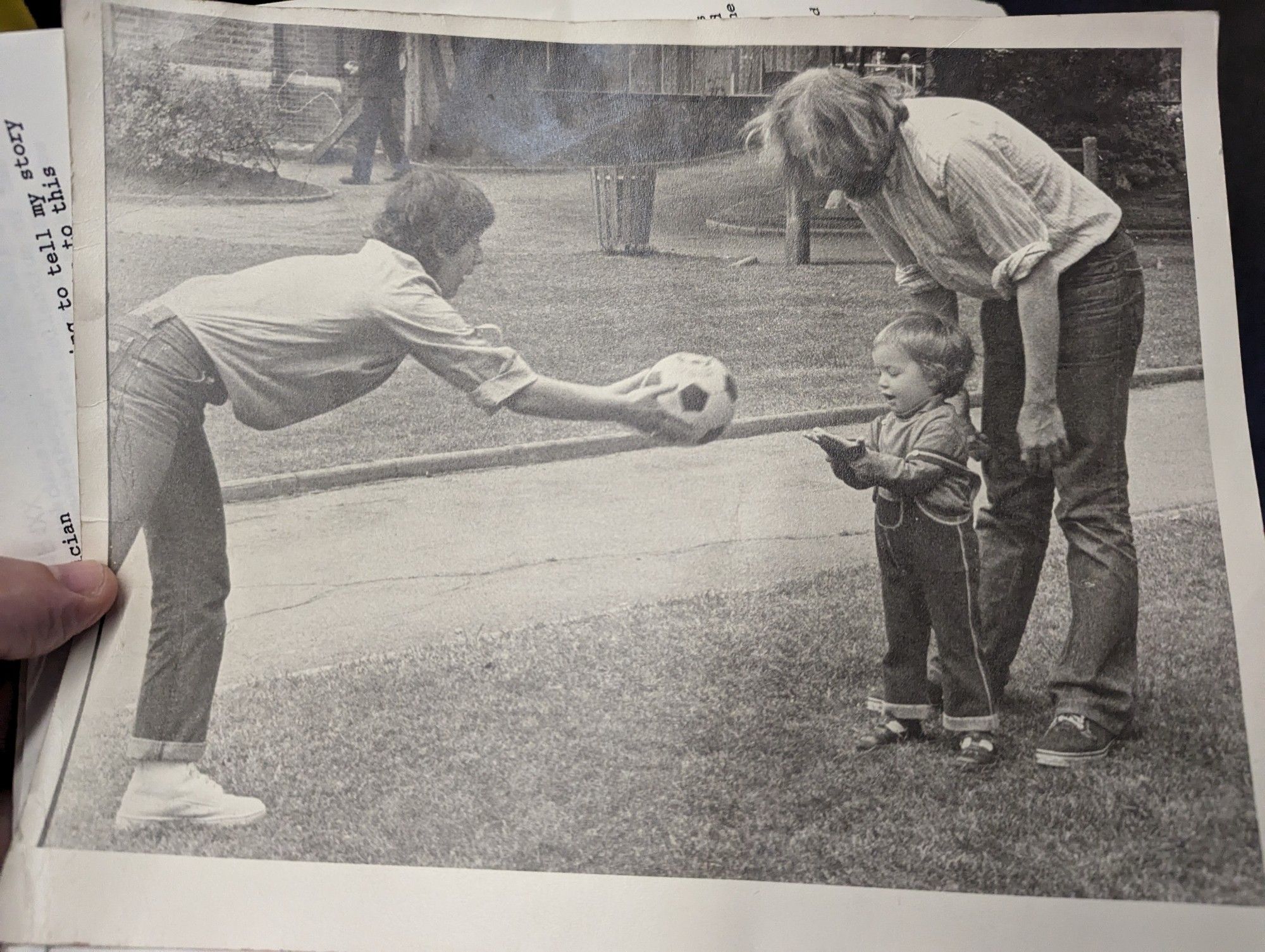 A young me, looking like I'm playing with a mobile before people even had computers, in a park with my dad Tony and his band mate Josefina and a classic 80s flyaway football