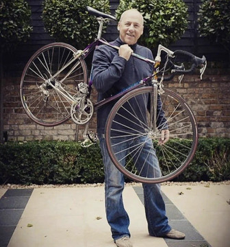 Photo of a man holding a bicycle on his shoulder.