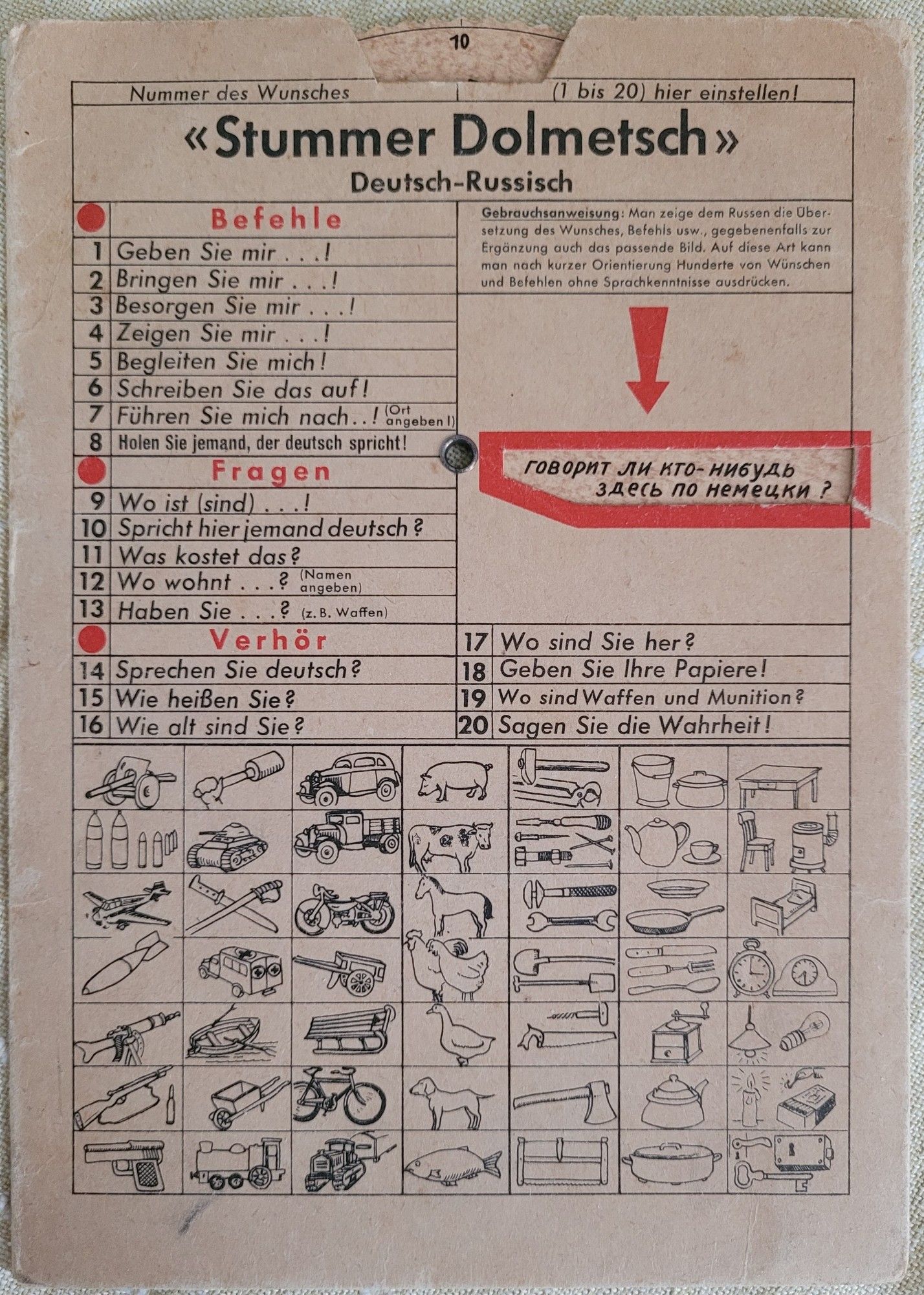 Ein "Stummer Dolmetsch" Deutsch-Russisch aus dem 2. Weltkrieg. Eine beidseitig bedruckte Pappkarte mit Drehscheibe, Piktogrammen und Sätzen wie: "Besorgen Sie mir...!", "Spricht hier jemand deutsch?", "Sagen Sie die Wahrheit!", "Wo sind Waffen und Munition?", "Wir brauchen Futter u. Stroh!", "Wo sind Minenfelder?" etc.