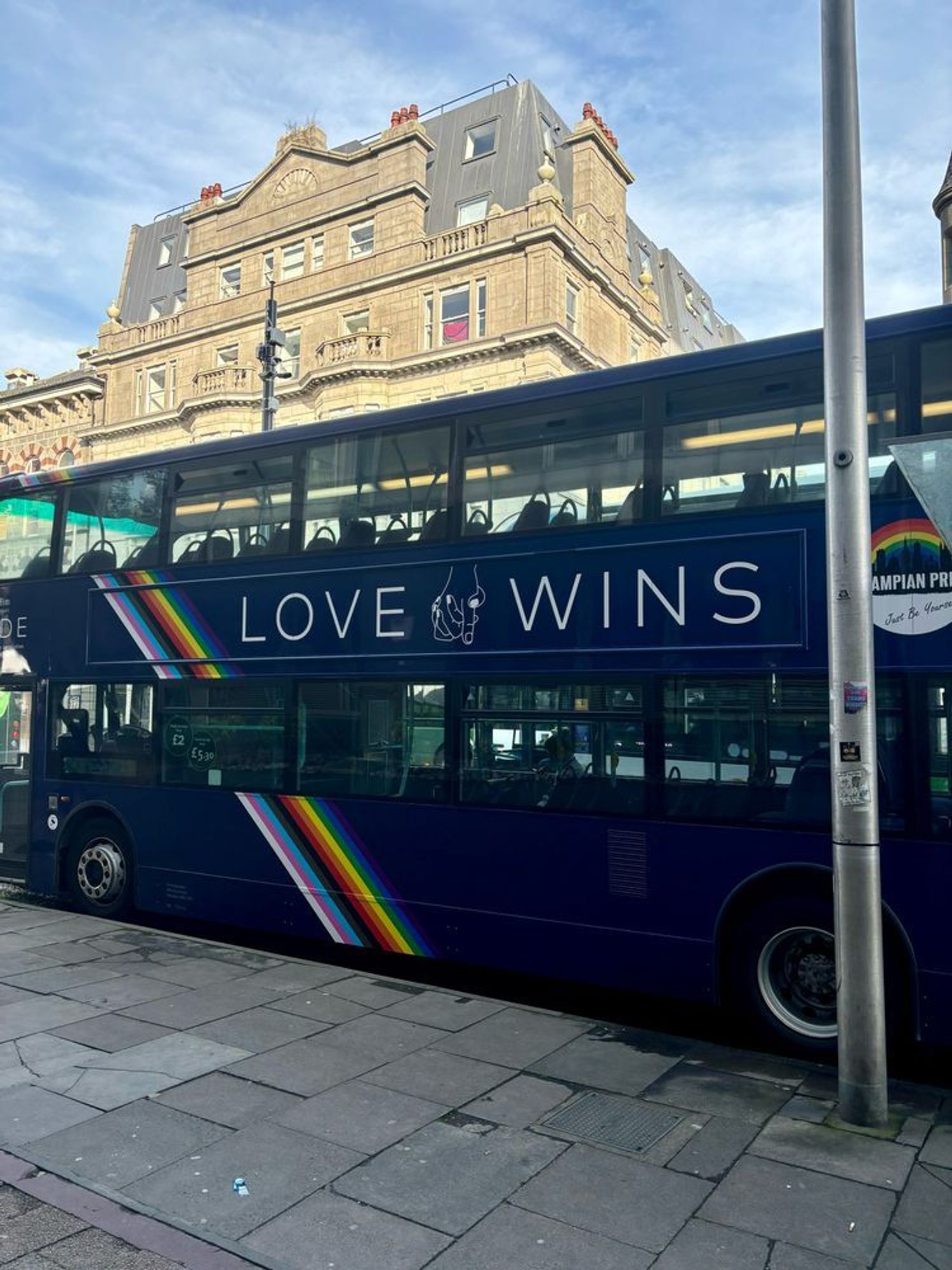 A double decker bus featuring two hands holding each other, a rainbow design, the Grampian Pride badge and the slogan LOVE WINS.