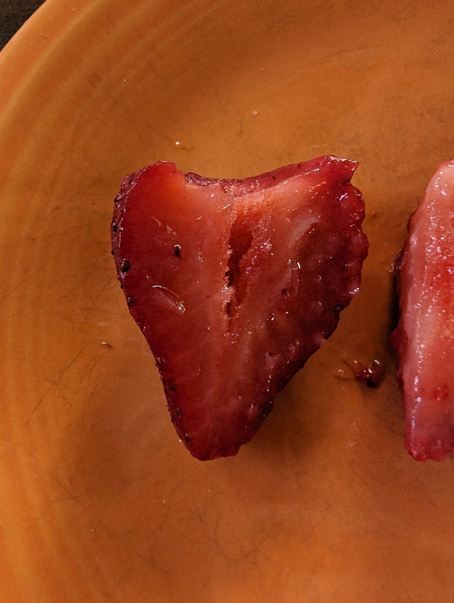 A closeup of a strawberry cut in half, it looks very wet