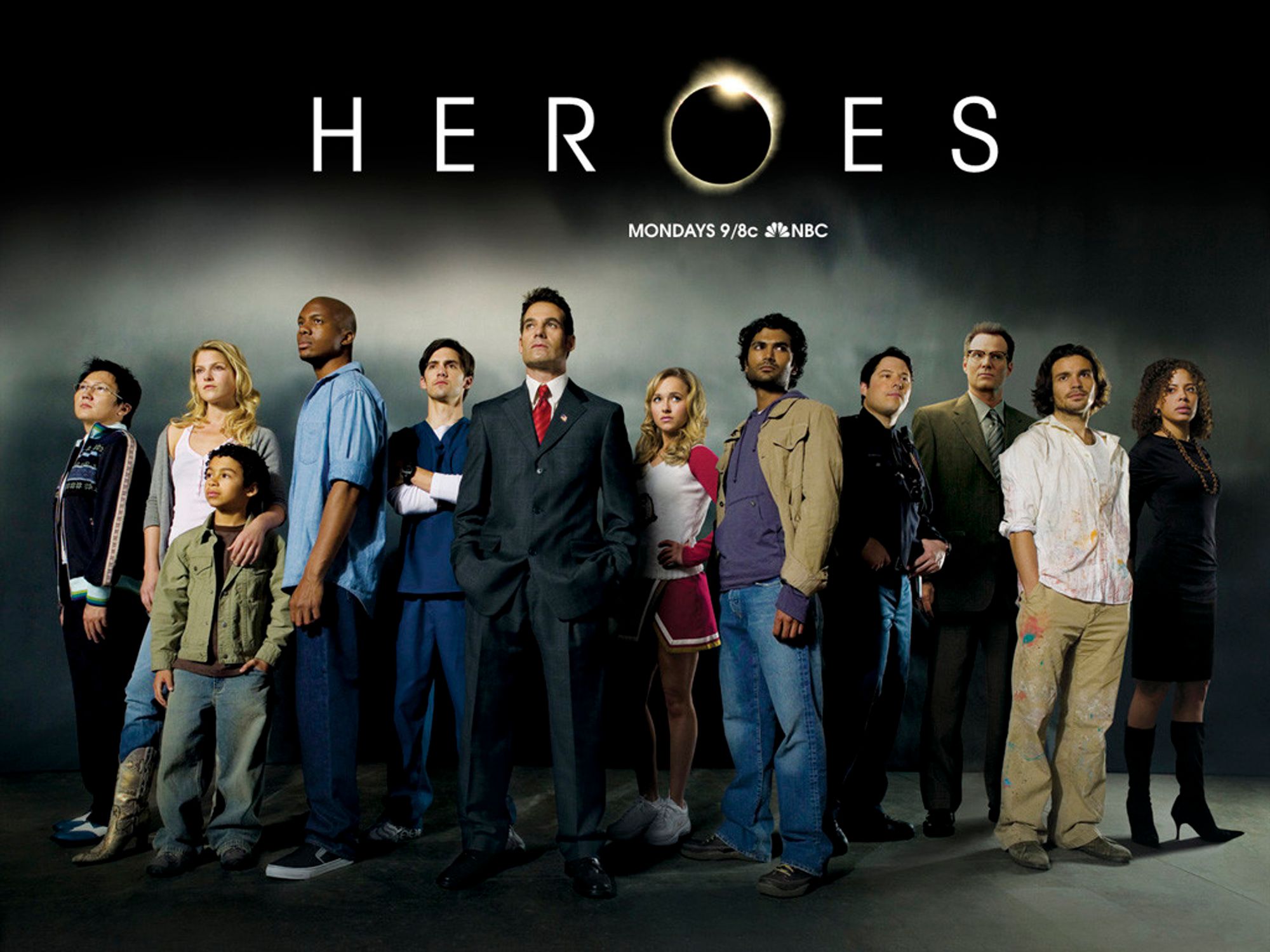 Immagine di presentazione della serie "Heroes" con i protagonisti in fila, vestiti normalmente, che guardano verso il cielo tutti in direzioni diverse.
Il logo-titolo della serie è la parola "HEROES" scritta in maiuscolo e con la "O" sostituita dall'immagine di un'eclissi di sole, simbolo della serie.