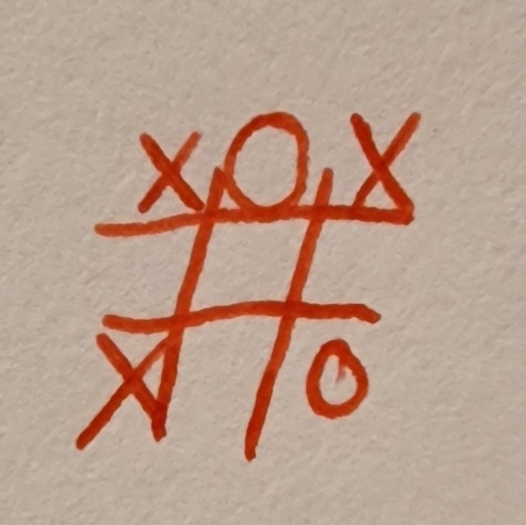 A bad drawing in red ink of crosses and naughts. It has X in 3 corners, O in the left bottom corner and O in the top middle. The rest of the playing field is empty. 