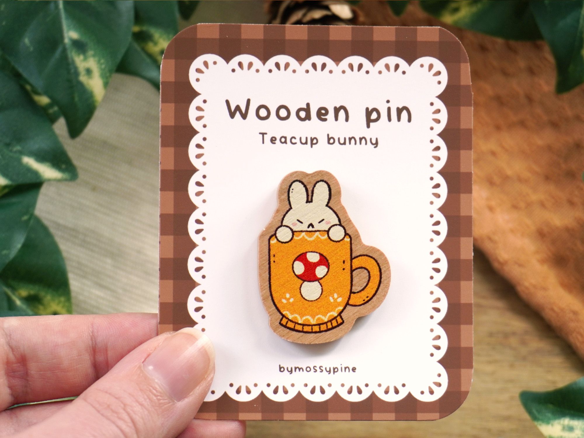 Product photo of a wooden pin: a yellow cup with a mushroom, inside hides a white bunny