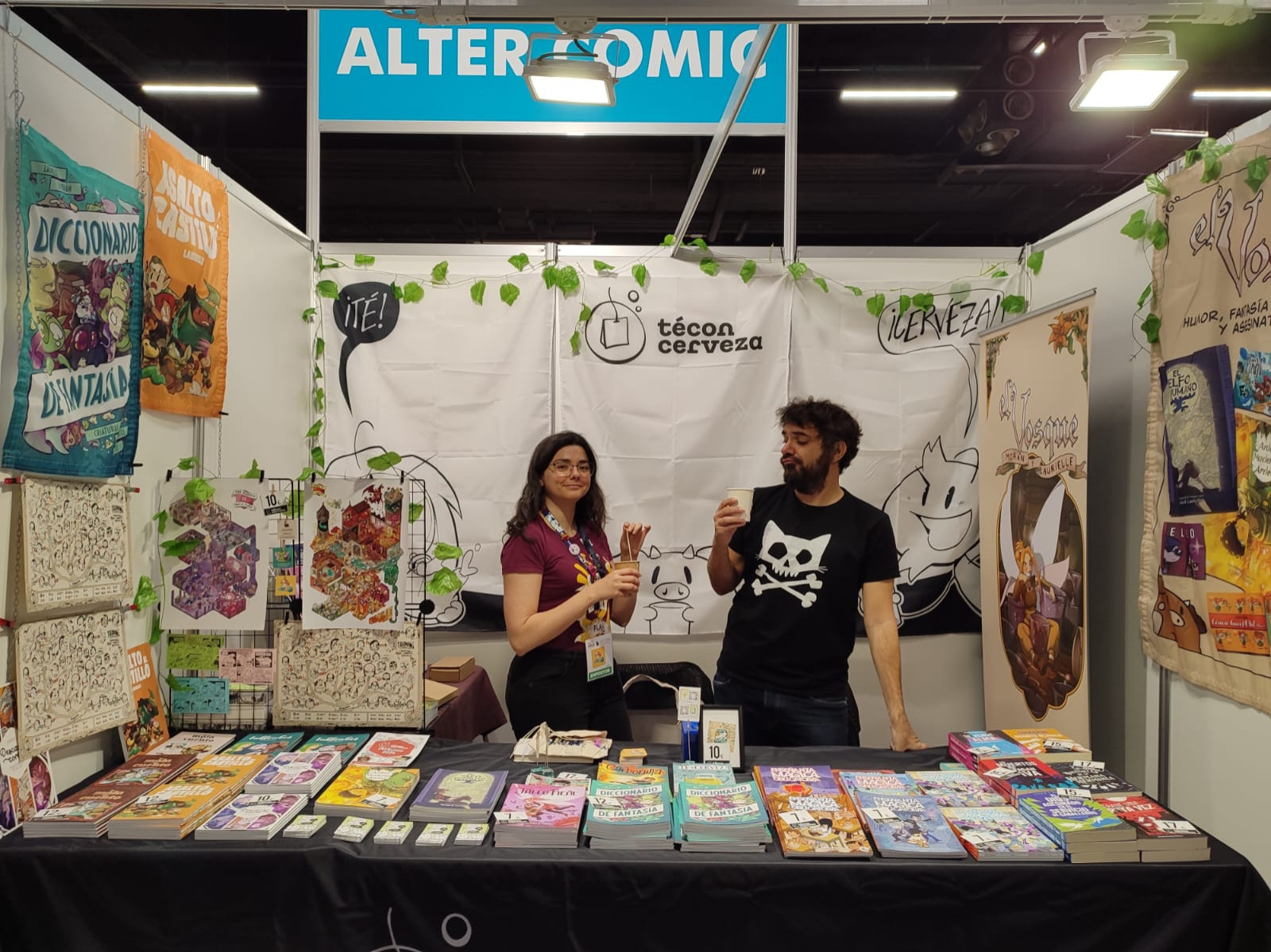 Foto del stand de té con cerveza en la zona Alter Cómic con Laurielle bebiendo té y Morán café en mano