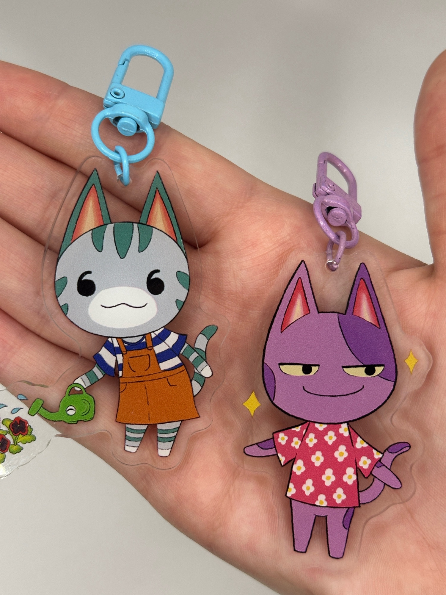 Keyrings of Lolly the cat watering flowers and Bob the cat being cool